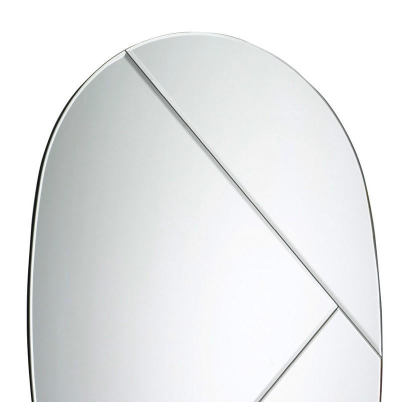 This exquisite mirror is an exercise in sleek sophistication. Its oval silhouette features no frame for a Minimalist and contemporary flair. The singular decorative element is the two intersecting diagonals on the smooth glass of the mirror,