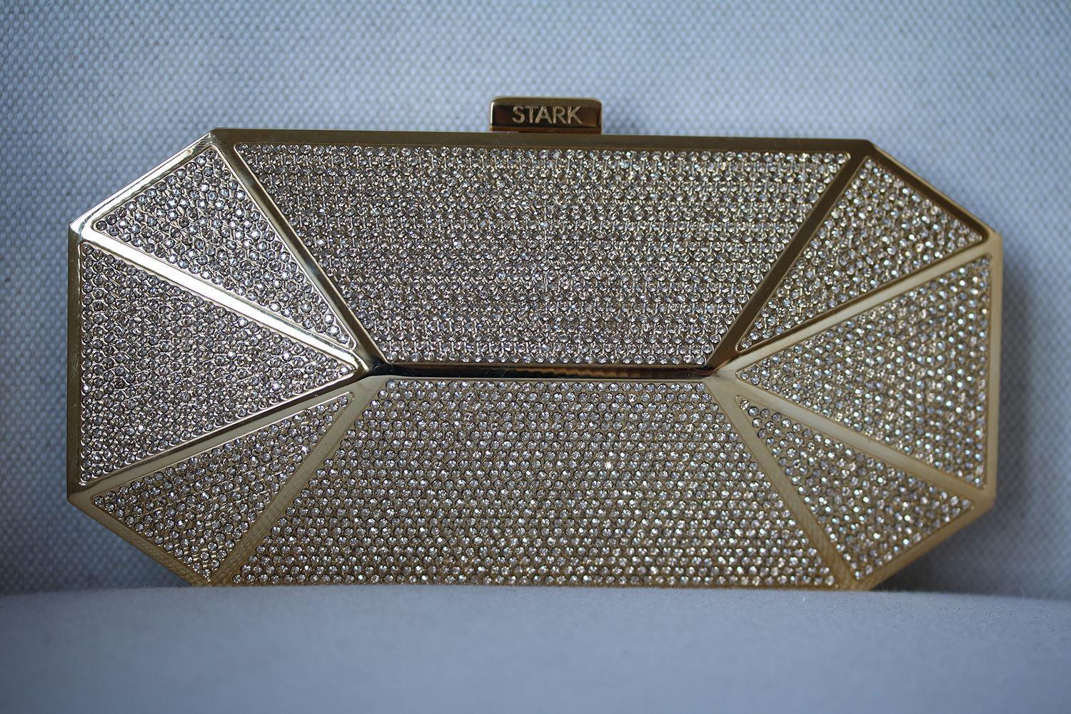 Stark hammered gold tone crystal box clutch. Swarovski crystal panels, engraved designer logo, fully lined. Clasp fastening at top. Colour: gold.

Condition: As new condition, no sign of wear. 