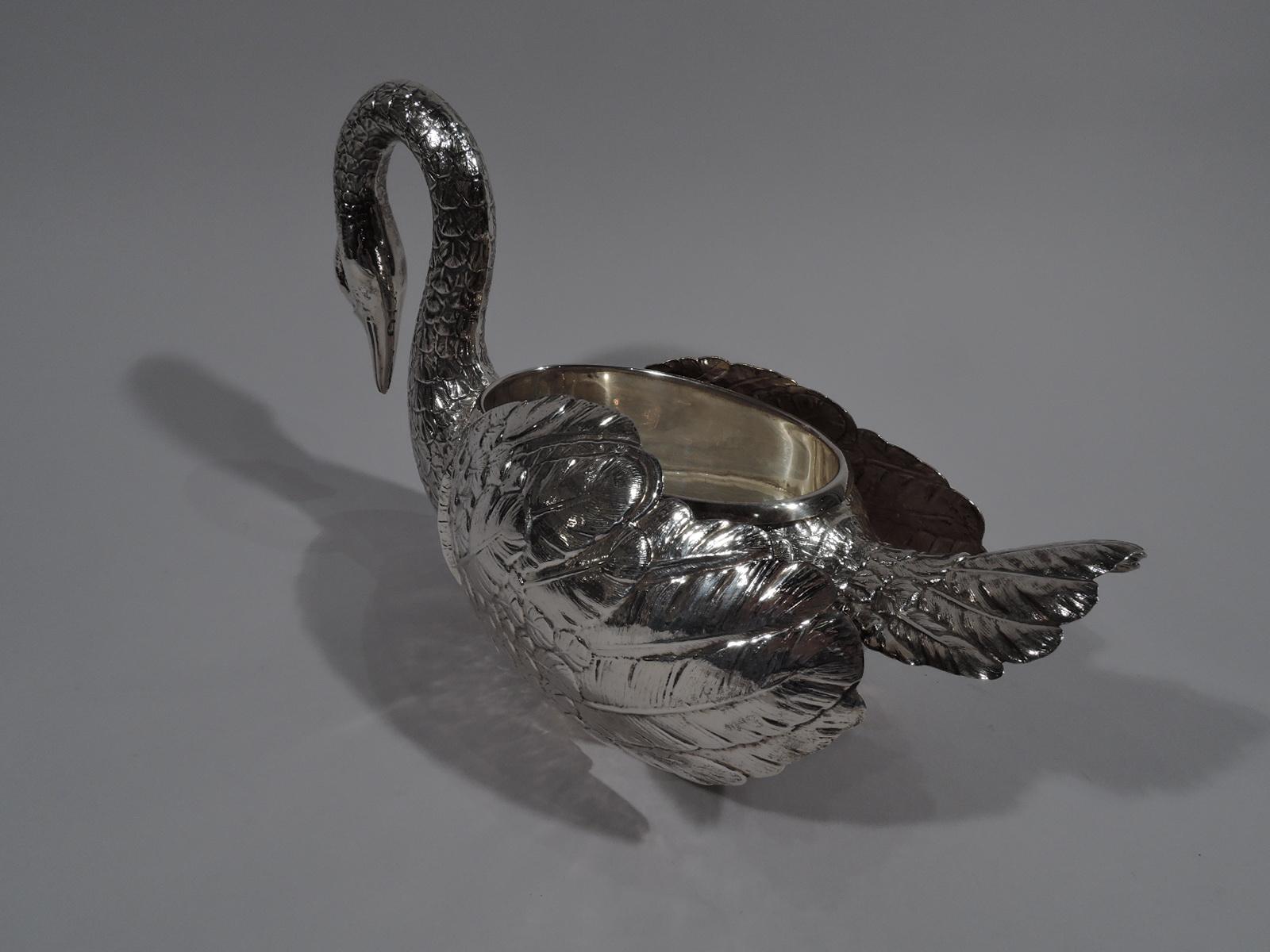 Stately sterling silver swan. Oval body with gracefully scrolled neck terminating in closed bill. Erect tail feathers and hinged wings. Beautiful plumage as befits an elegant table companion. Body hollow with detachable liner for holding special
