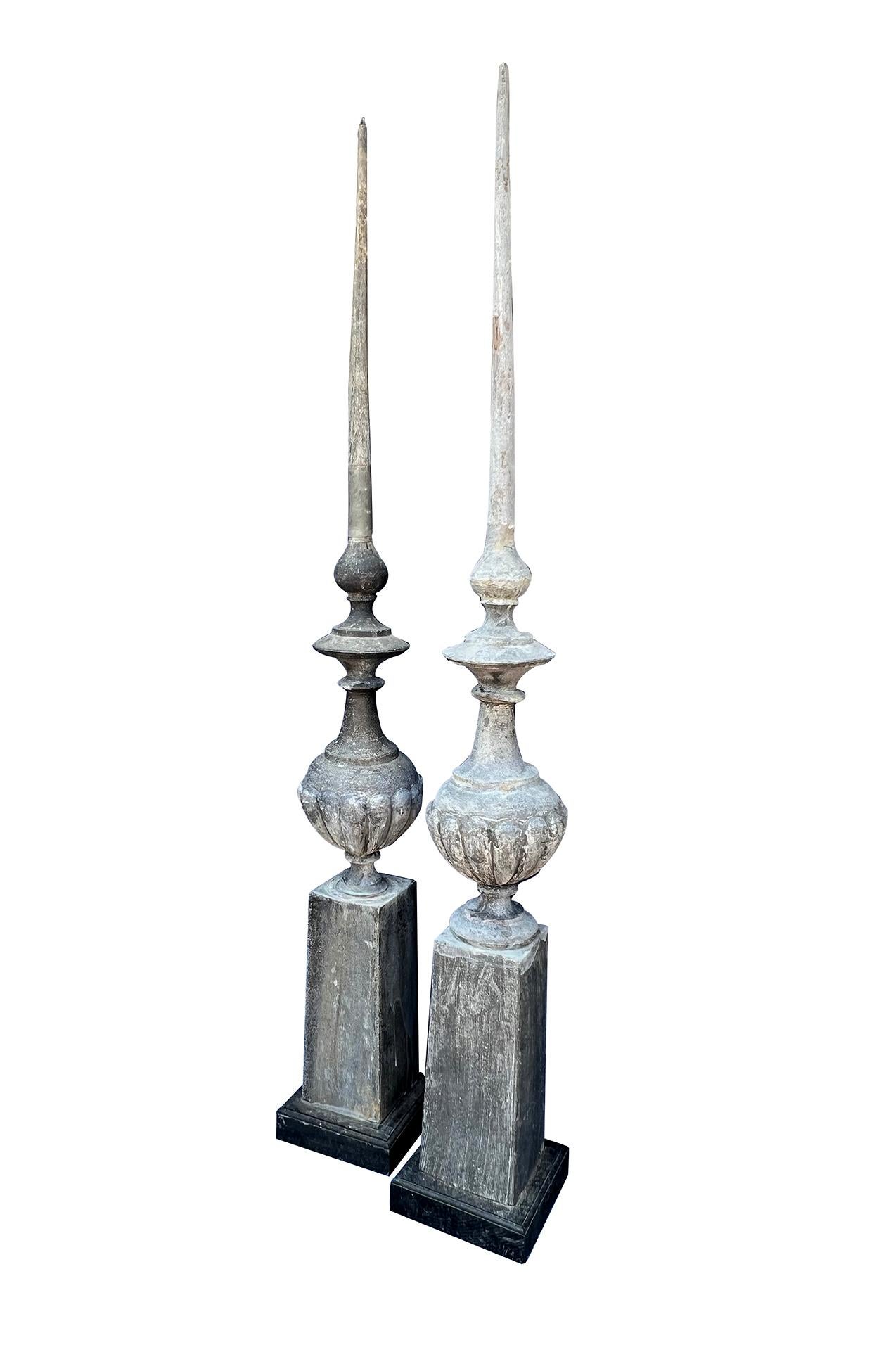 each tall finial with pointed spire above a lobed baluster-form mid-section resting on a graduated square base; the whole on later ebonized wooden plinths
