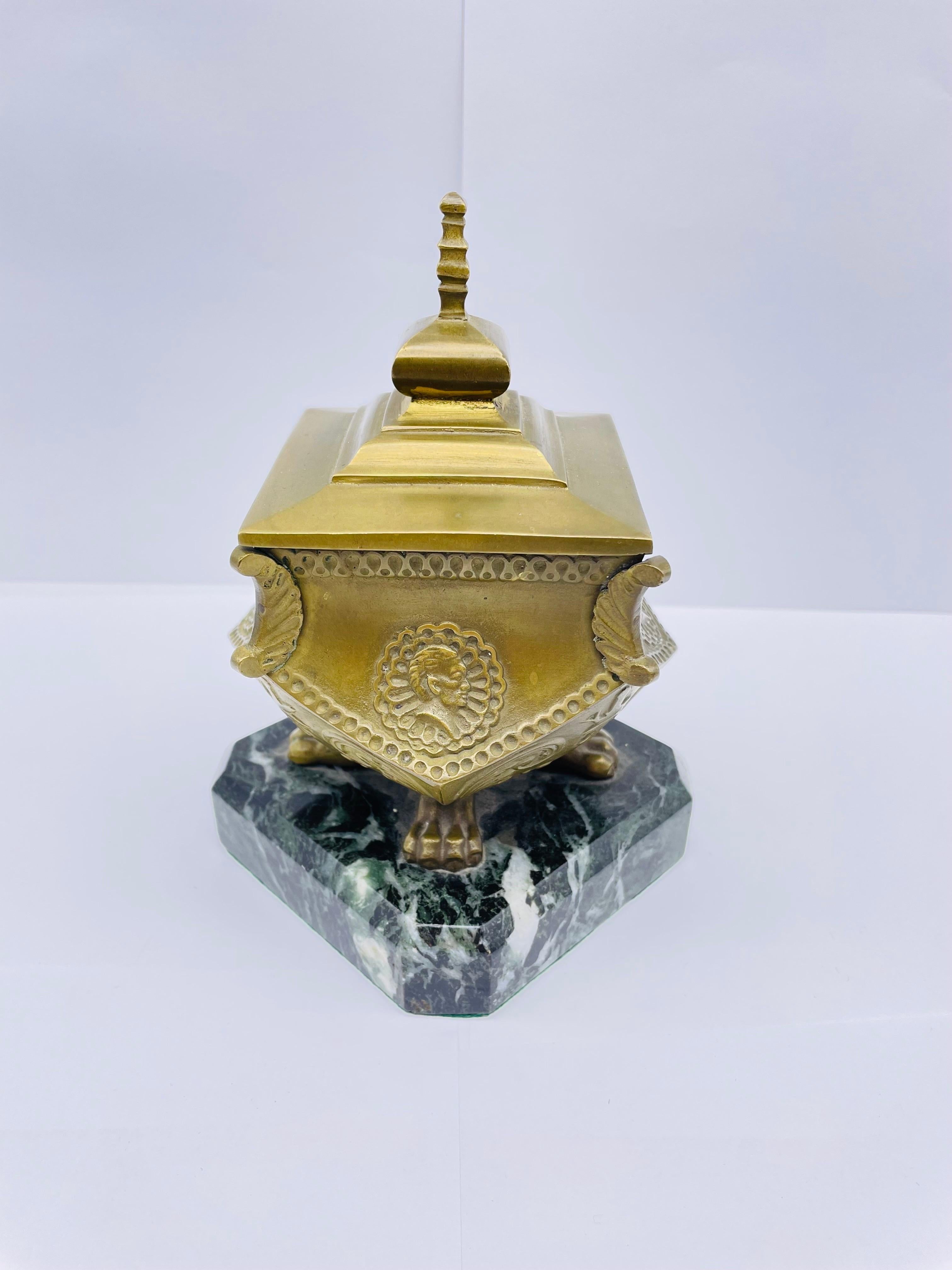 Stately antique brass bronze inkwell around 1880

Solid brass bronze inkwell with lid. Original glass insert.
Inkwell with paw feet standing on a square molded marble base.

Very noble and stately.