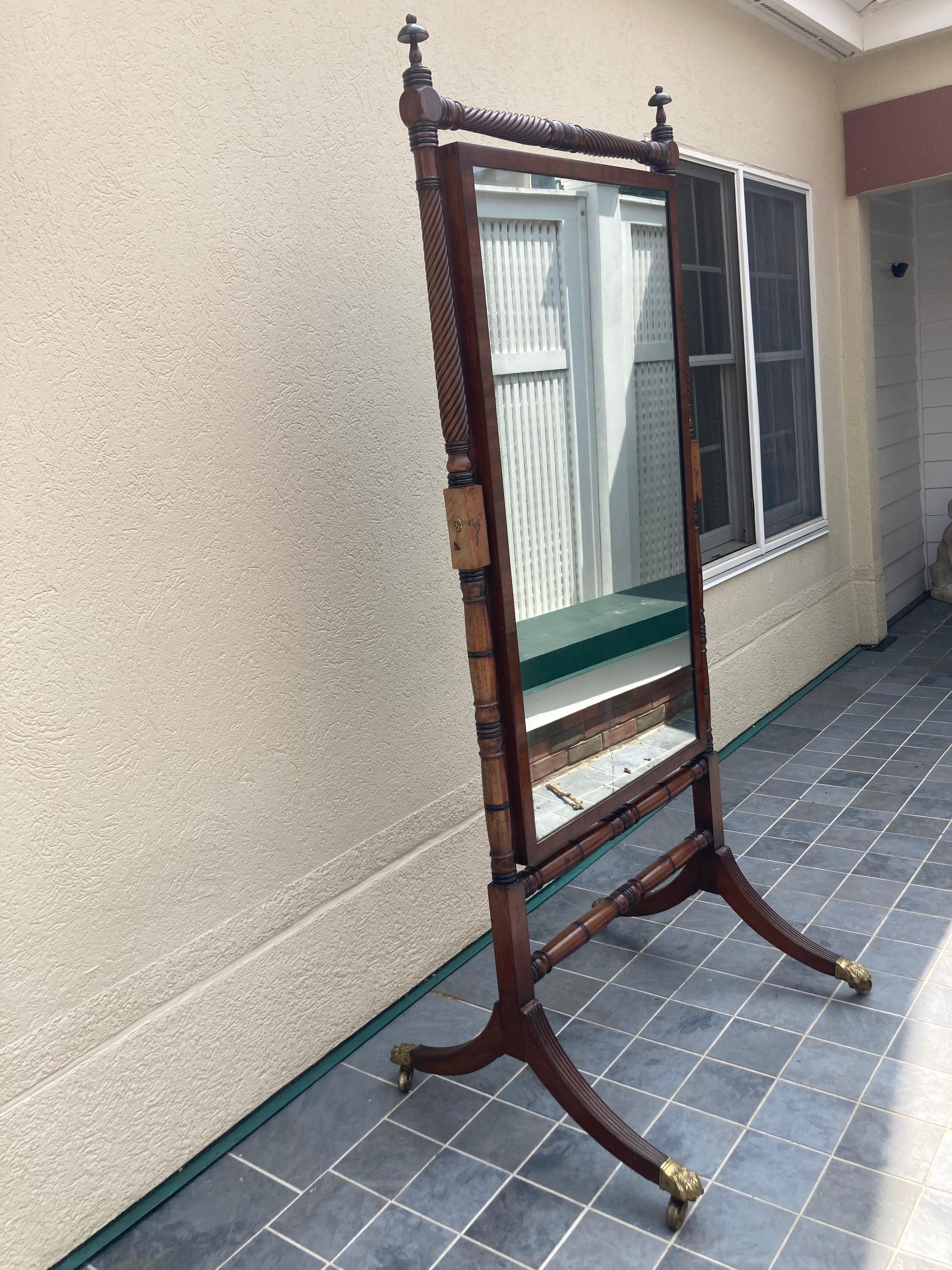 Classic Regency style Cheval floor mirror having a turned mahogany frame with block and spindle supports with handsome finials holding a pivoting mirror in a molded frame. Frame ending in brass claw feet on casters. 

Mirror only: 
25.75” wt