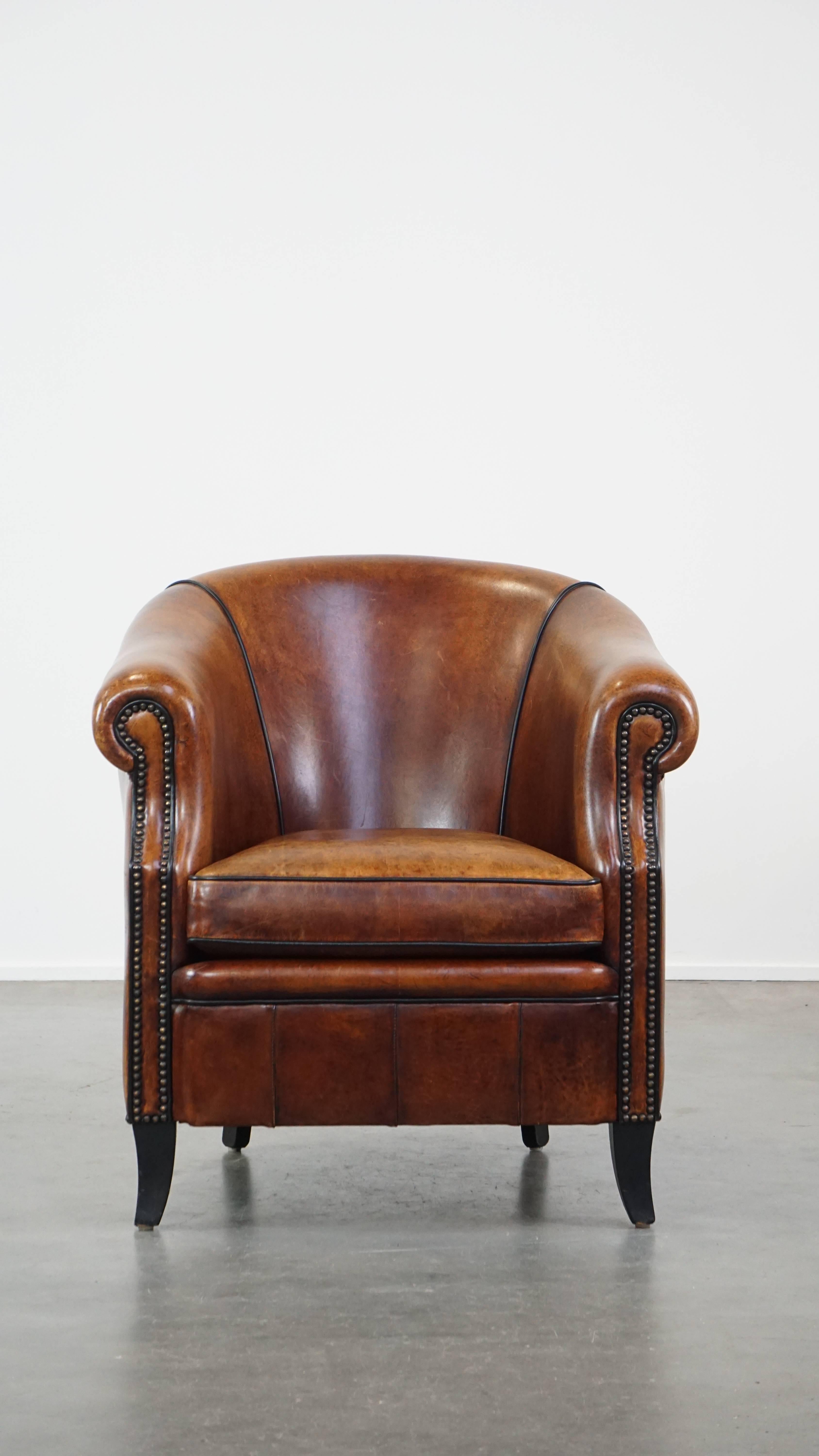 Este maravilloso sillón club, de piel de oveja, encaja fácilmente en casi cualquier interior. Presenta un bello acabado con clavos decorativos y ribetes negros, que desprende lujo y majestuosidad. La silla está equipada con un cojín de asiento