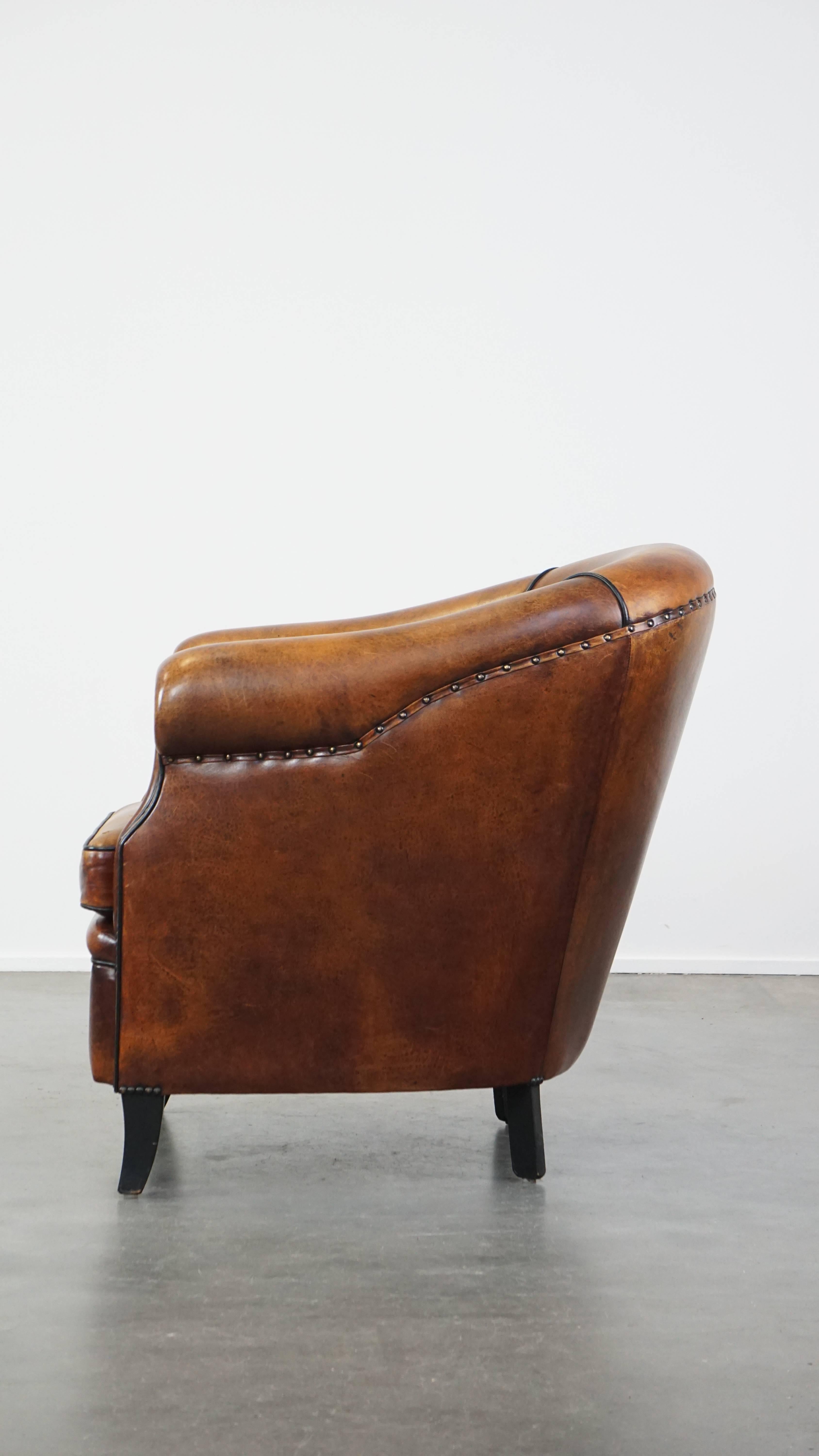 Majestuoso sillón club de piel de cordero acabado con clavos decorativos y ribete negro siglo XX en venta
