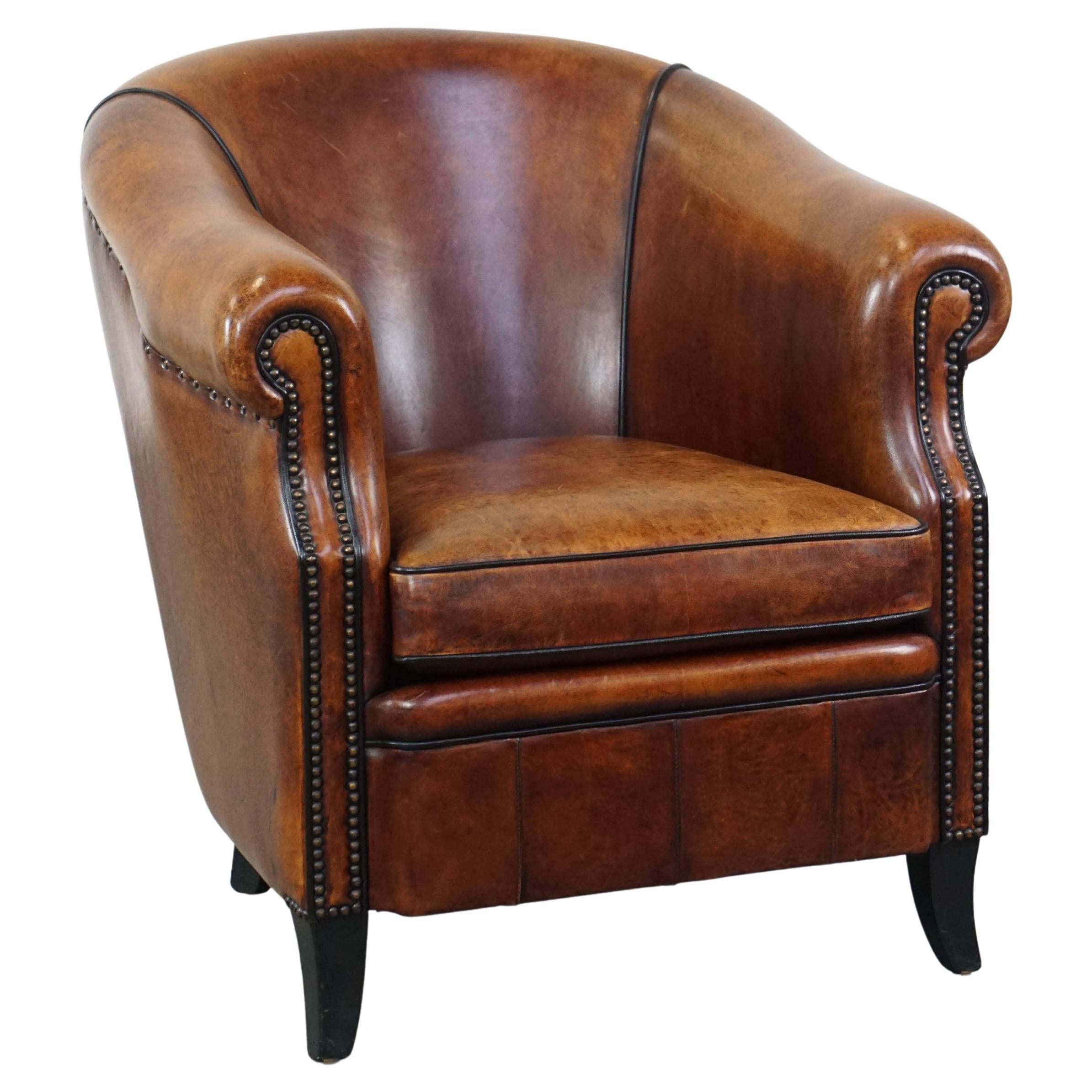 Stately sheepskin club armchair finished with decorative nails and black piping