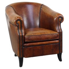 Stately sheepskin club armchair finished with decorative nails and black piping