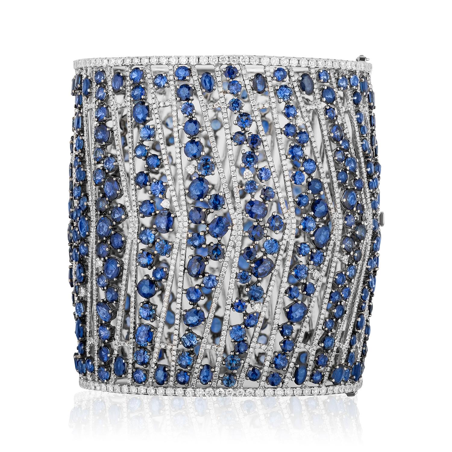 Beautiful and Unique Wide Cuff Bangle.

Featuring a cascade of Round, Oval and Cushion Sapphires of different blue hues weighing 94.10 Carats.
Spaced with clean white lines of Round Brilliant Diamonds weighing 15.80 Carats.

109.90 Carat Total