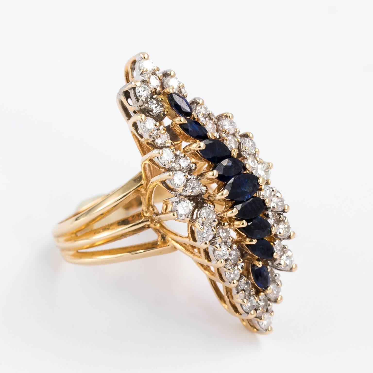Circa 1970s statement ring made from high quality natural diamonds and sapphires. There are 36 2 mm or 3 points round brilliant cut diamonds, two 2.5 mm or 5 points round brilliant diamonds showcasing an array of marquise cut rich royal blue natural