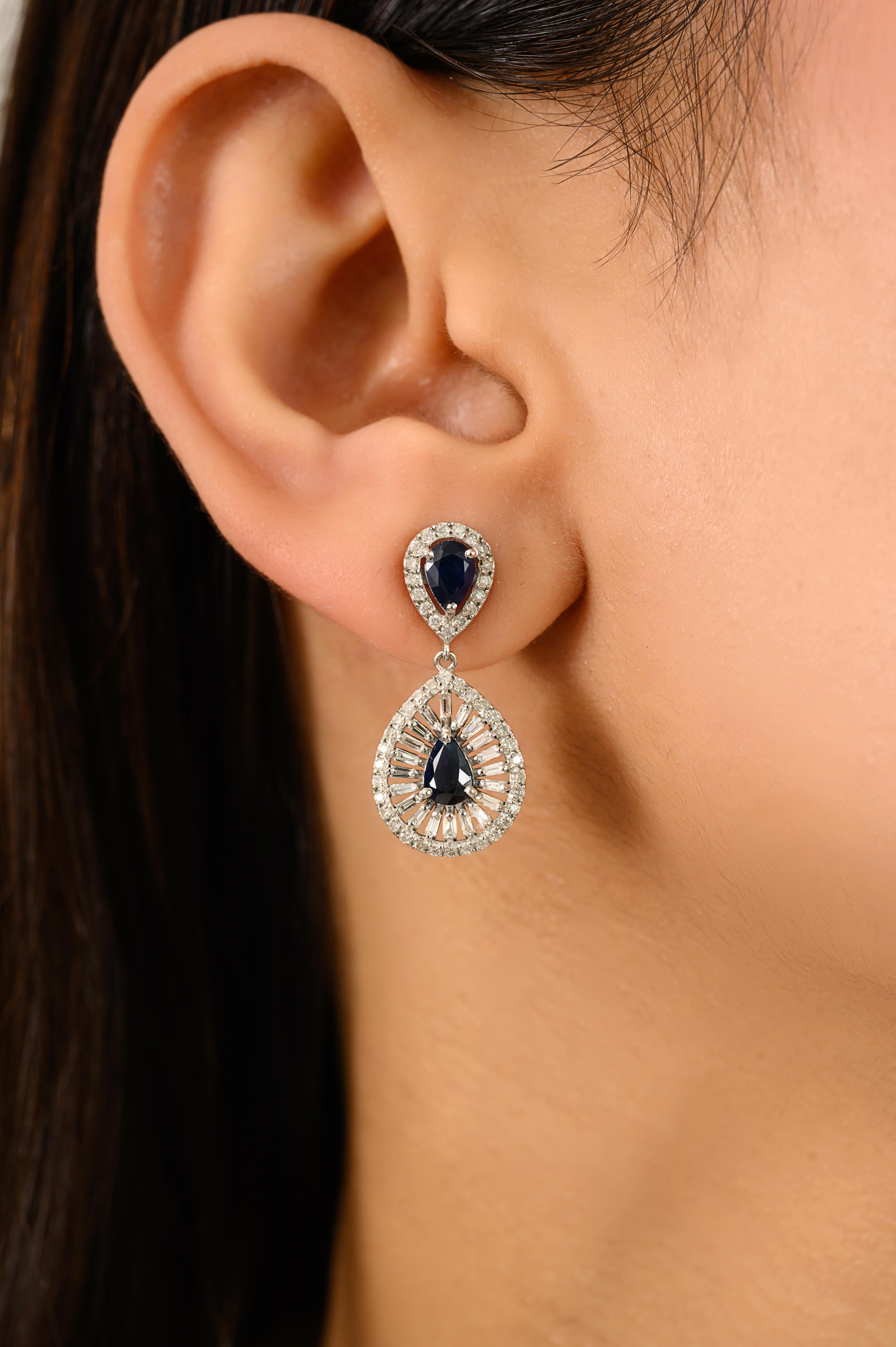 Ces boucles d'oreilles en or blanc 14k à halo de saphirs bleus taillés en poire et de diamants, fabriquées à la main en or blanc 14k luxueux, présentent un poids total de 1,90 carat de saphirs bleus taillés en poire, entourés de 1,01 carat de