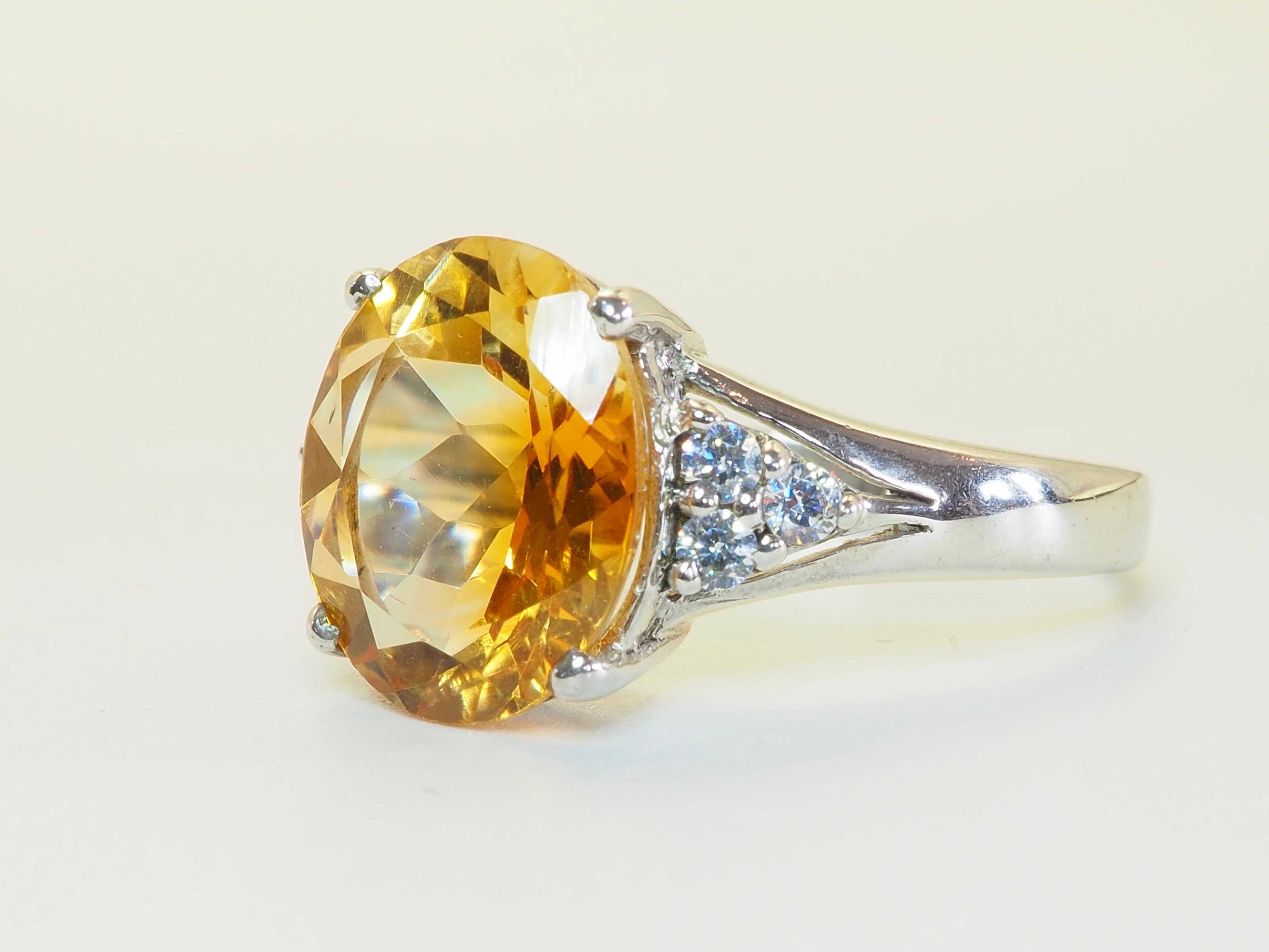 Strahlender Statement-Ring mit einem 3,94-karätigen Ensemble aus goldenem Citrin und strahlend weißem Quarz. Das Herzstück - eine ovale, facettierte Zitrine - leuchtet in warmen Bernsteintönen, die durch den geschickten Schliff ein Maximum an Feuer