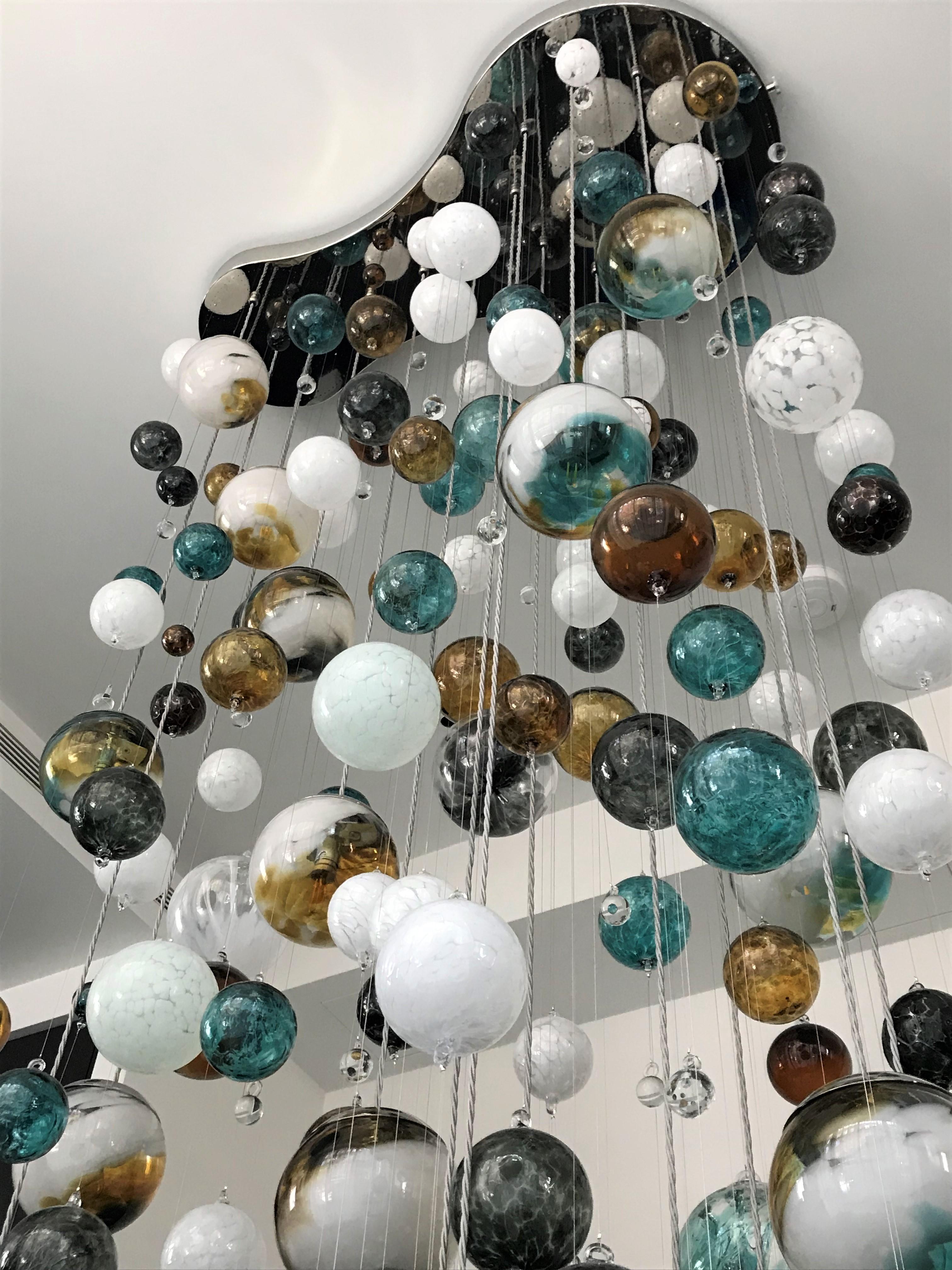 This contemporary chandelier is a Cascade design and features individually blown glass spheres. The glass is blown in Europe and the UK and the chandelier is designed and handcrafted in our studio in South London. 

This chandelier is an