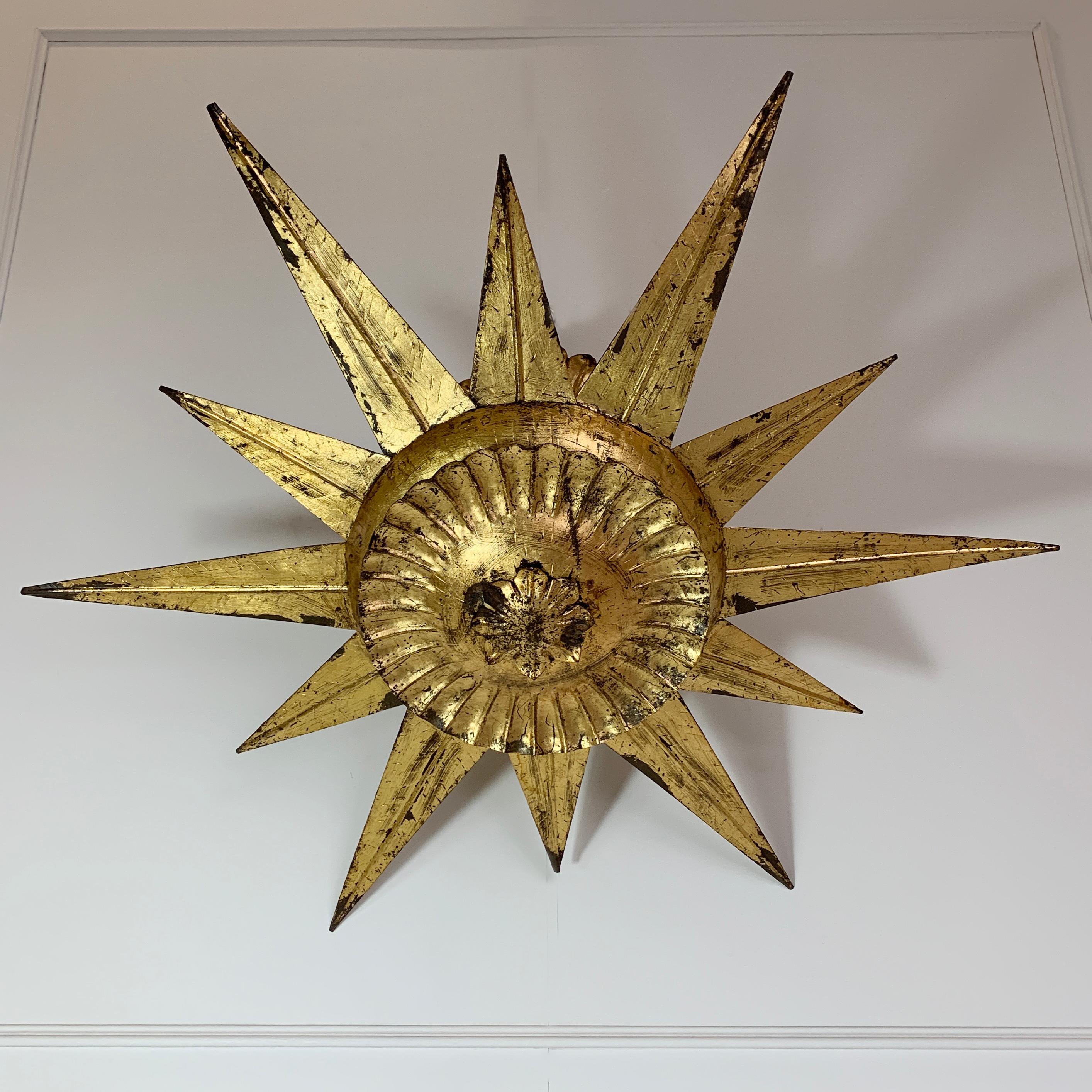 Beautiful gilt metal Spanish sunburst light
Bright gilt finish
Spain, 1950s
This is a beautiful and rare design
Large size sunburst ceiling light on a pendant stem
The light has a fixed ceiling rose with hook to attach the fixture to a ceiling