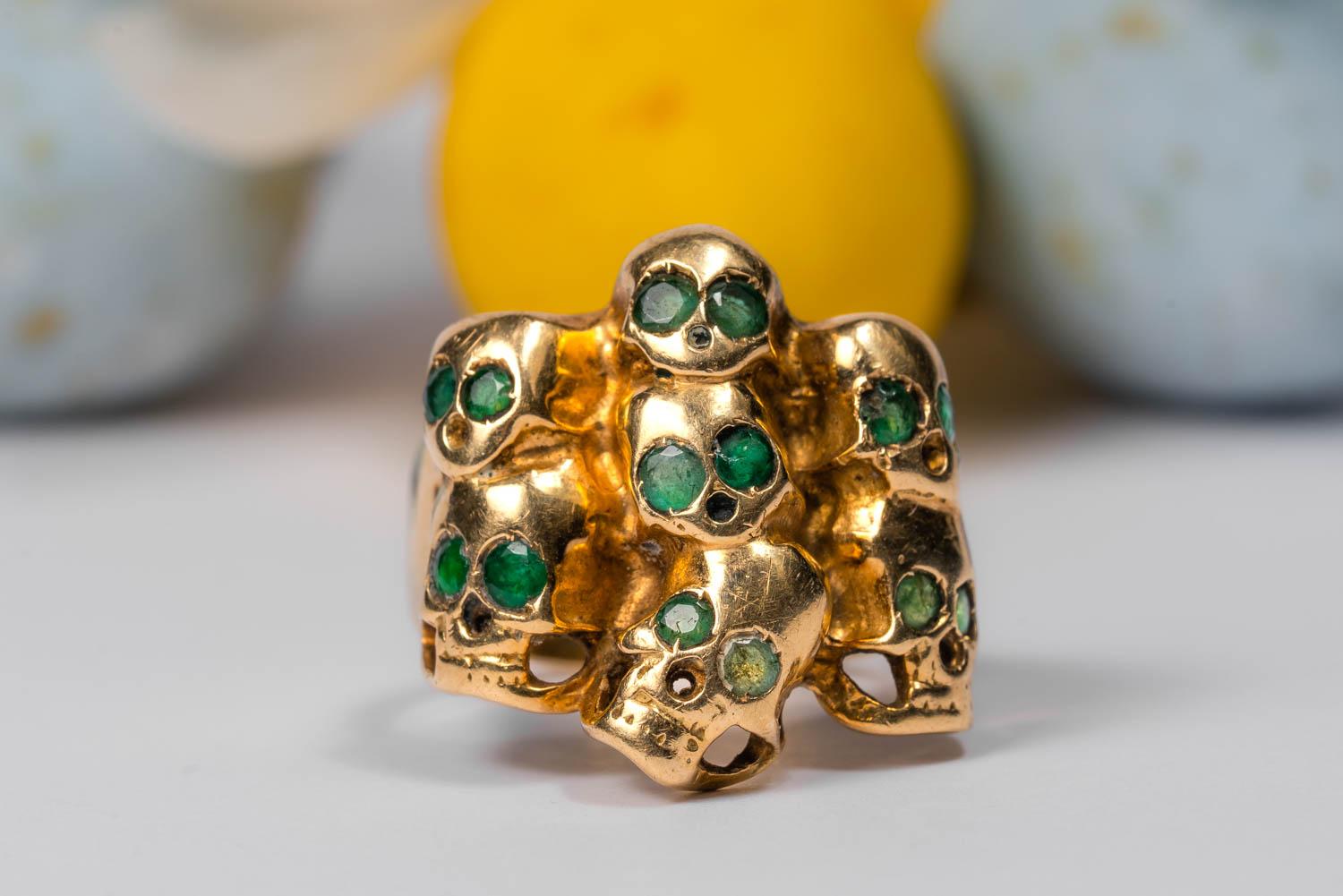 An ultimately naughty, but still somehow nice, solid 14k gold ring.

This massive ring weights almost 10 grams! Its crown measures 0.95 x 0.85 inches and is set with 9 skulls. Each skull has sparkling emerald eyes and look very