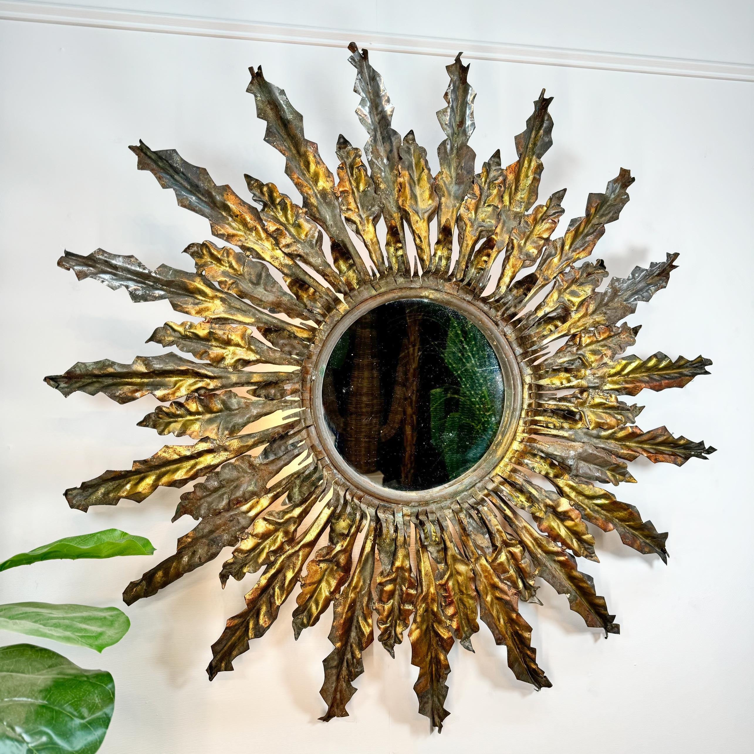 This truly incredible 1930's iron illuminating sunburst mirror has the most stunning age related patina, over the years the worn gilt, verdigris, rusting and wear have given this huge statement piece a beautiful overall patination, gold in many
