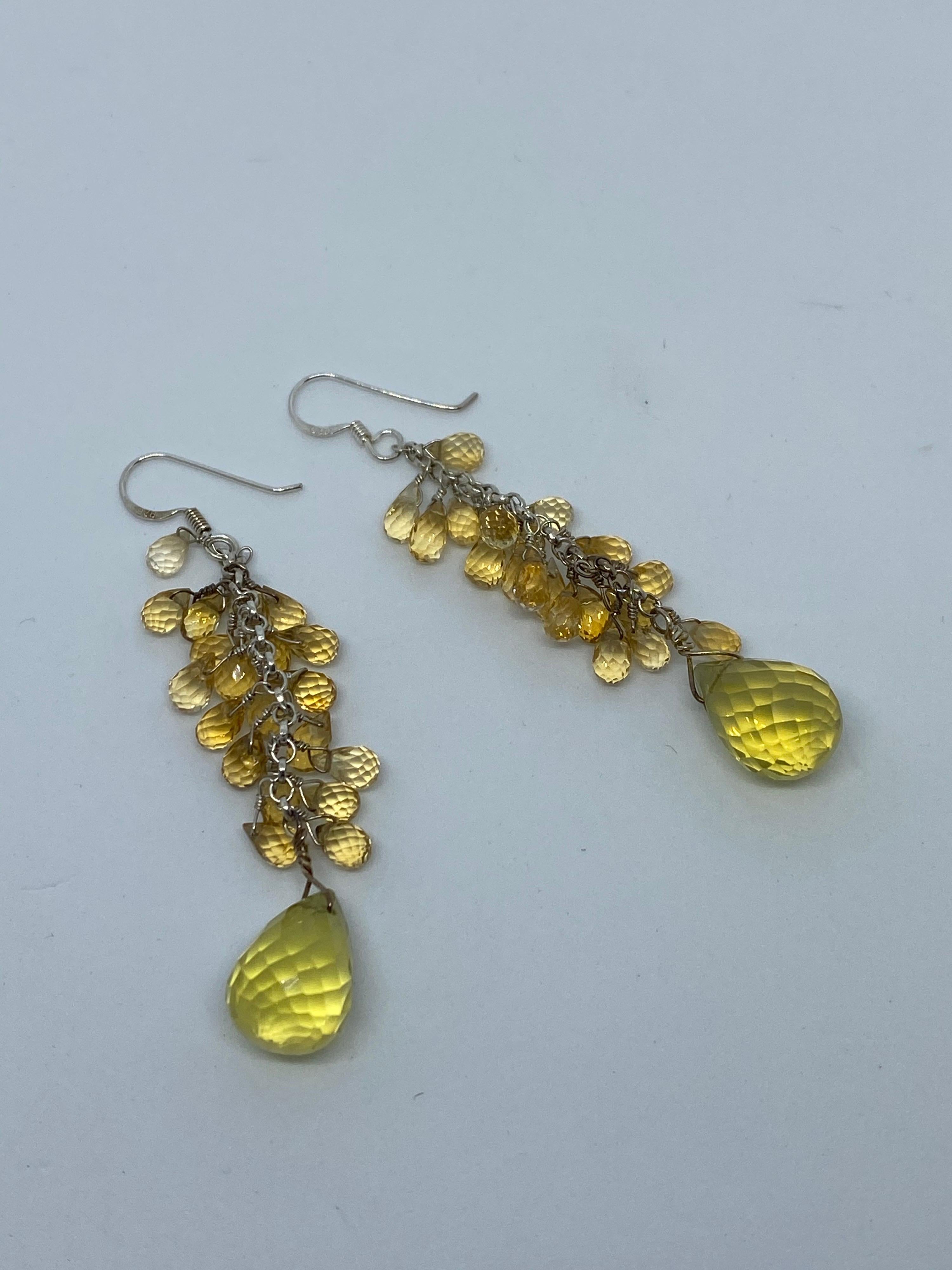 These earrings measure 3 inches in length and have a bold look with hues of yellow, brown, and green depending on the lighting. The Citrine Briolettes and hand-wired in Sterling Silver and lead down to the large Lemon Quartz Briolette Dangle. 