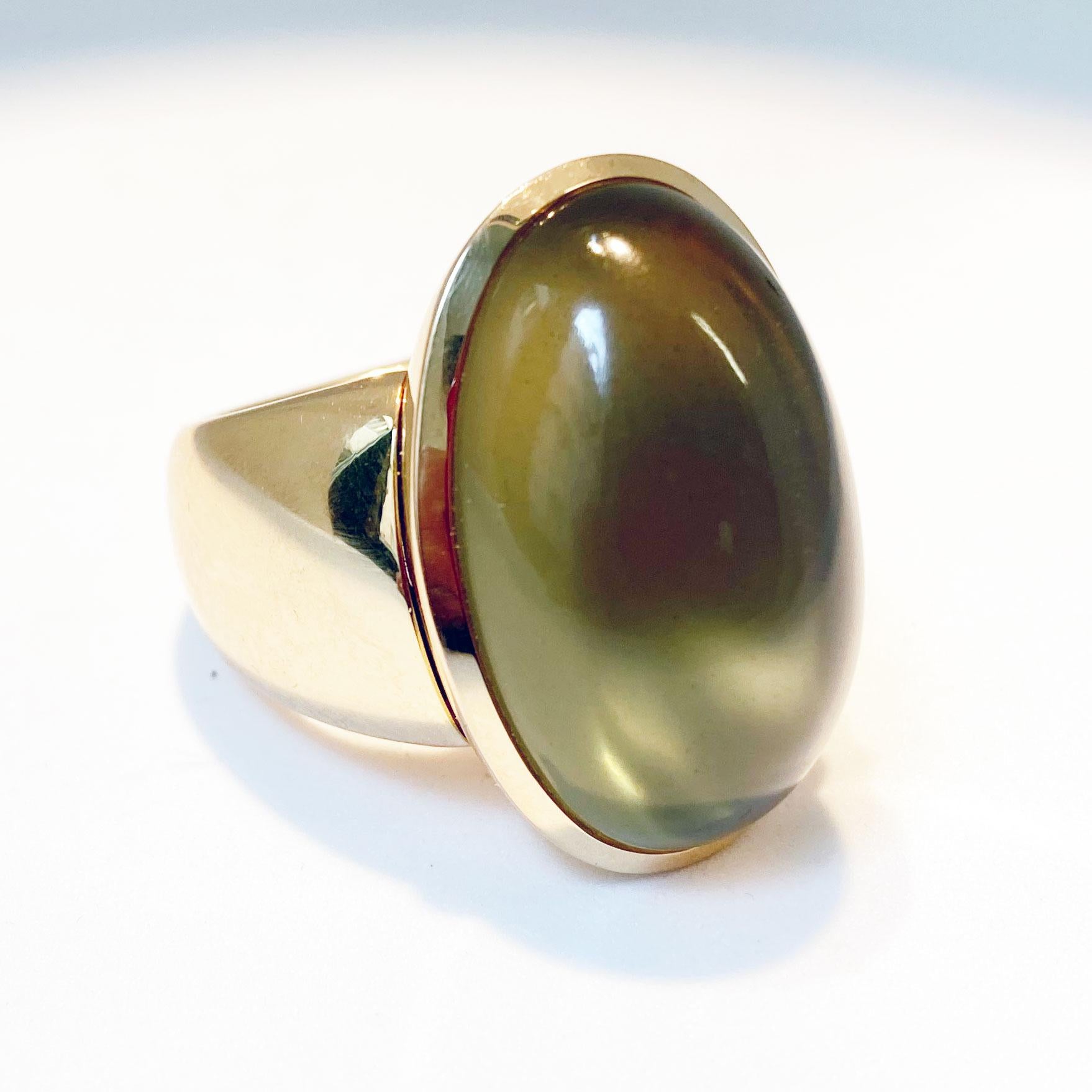 This stunning Ring convinces with pure simlicity.
As a fascinating and alluring centre part a bezel set ,semi translucent ,yellow-greenish Moonstone cabochon with a hefty weight of  34.75 ct.
The mystic shine is moving allover the stone.
Stone