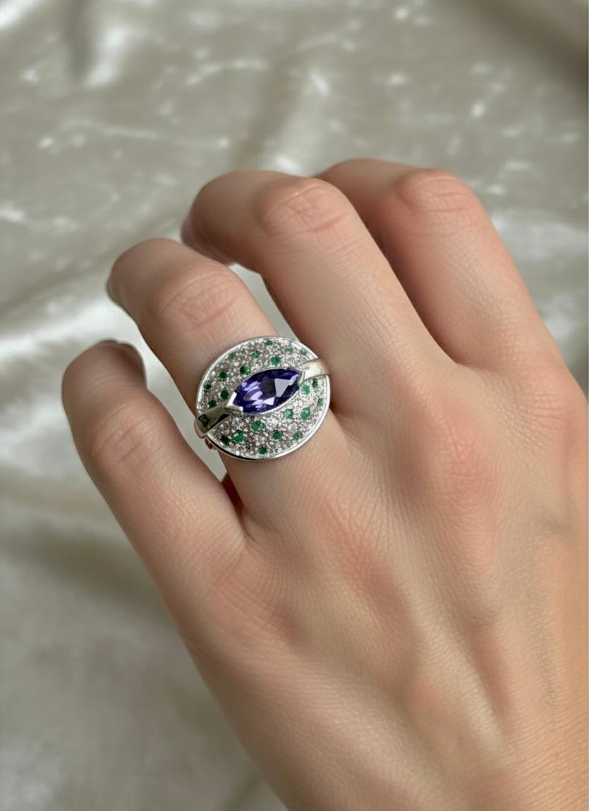 Setzen Sie ein Zeichen mit diesem atemberaubenden Cocktailring aus natürlichem Tansanit, Smaragd und Diamant. Gefertigt aus 18 Karat Weißgold, ist dies eine einzigartige und skulpturale Kreation mit einem eleganten 