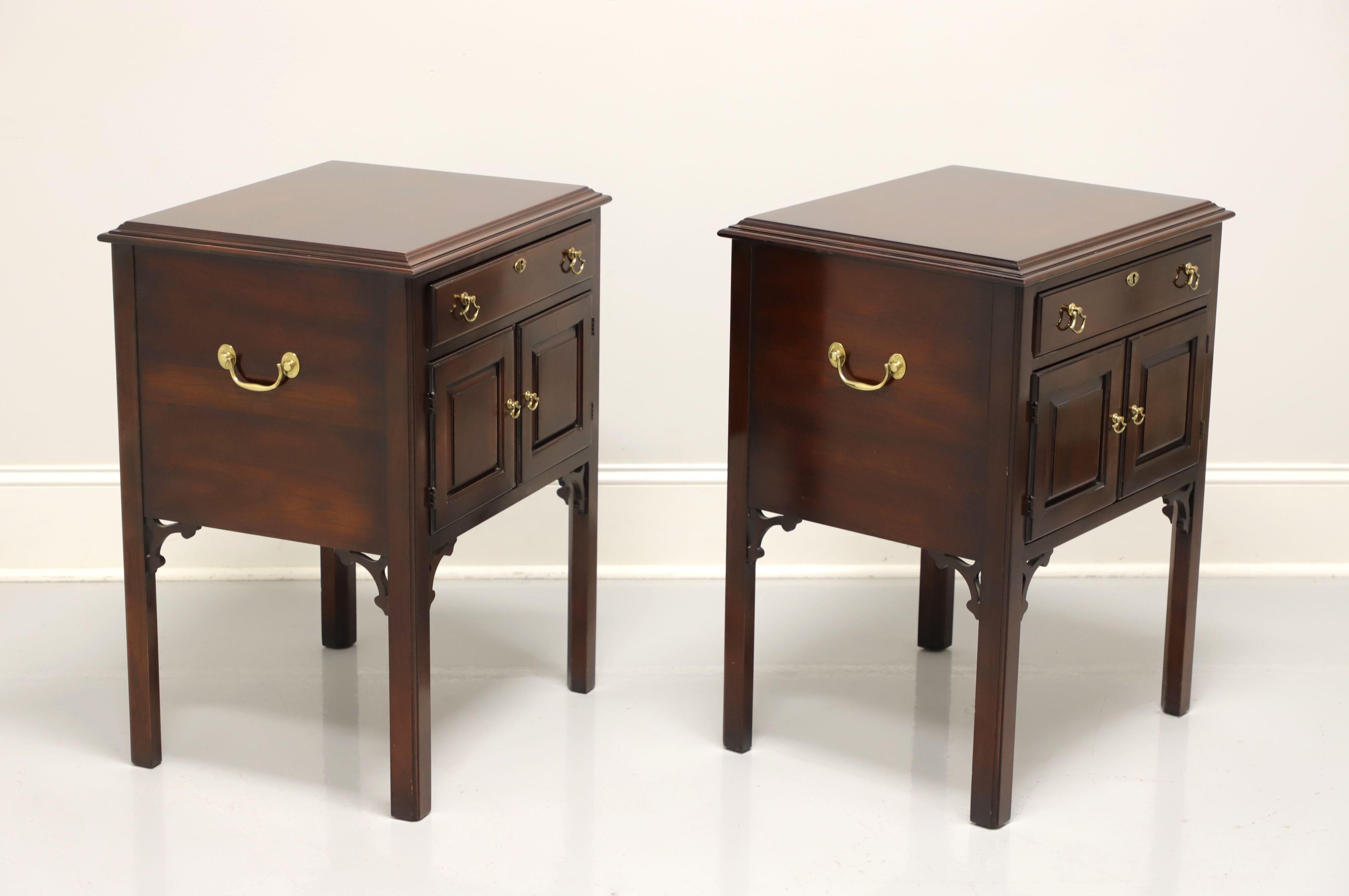 A pair of Chippendale style nightstands by Statton Furniture. Solid cherry with their Old Towne finish, fretwork to corners, straight legs, brass hardware and side handles. Features one drawer of dovetail construction with faux lockplate over a