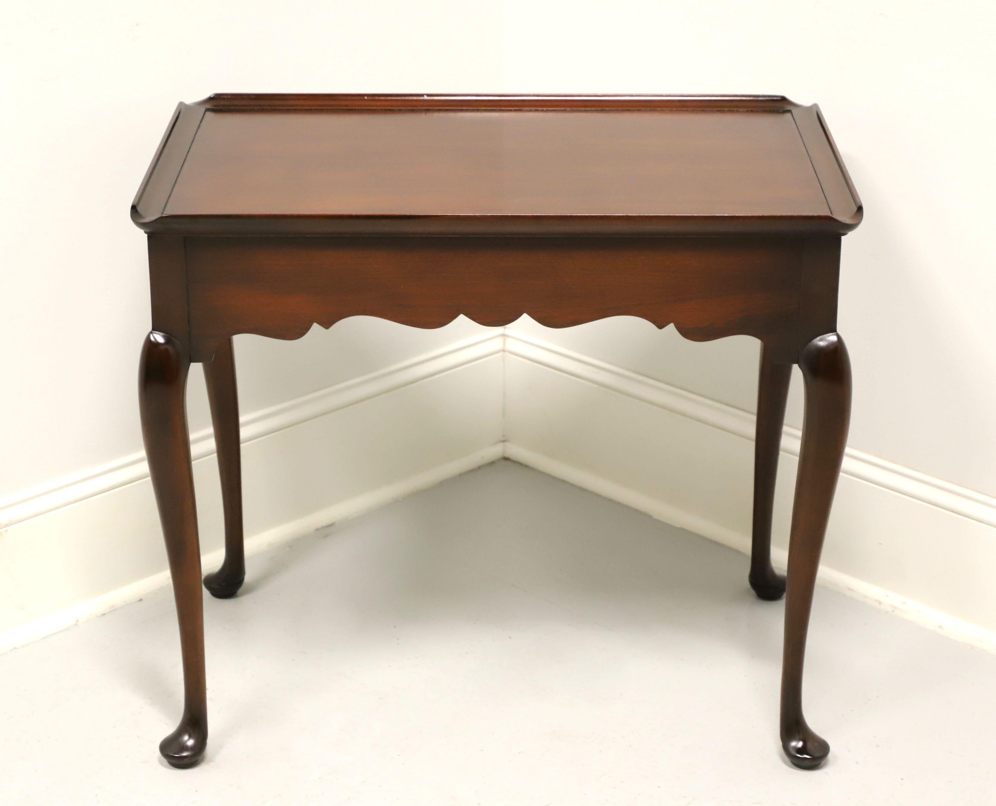 A tea table in the Queen Anne by Statton Furniture, of Hagerstown, Maryland, USA. Solid cherry with their Old Towne finish, two side slide out trays with brass knobs, carved apron, tapered legs and pad feet. Made in the late 20th