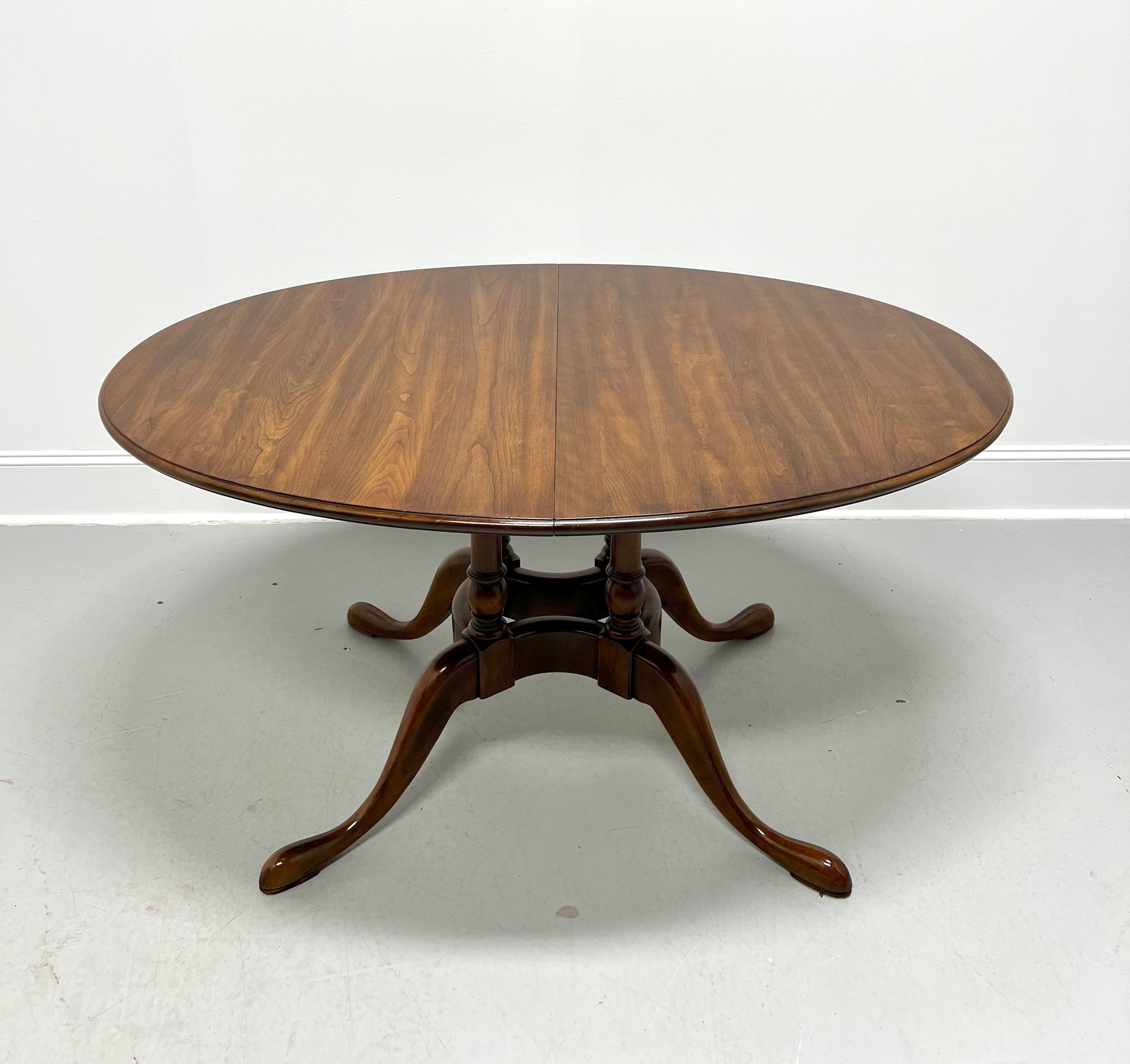 A Queen Anne style oval dining table by Statton Furniture. Solid cherry wood with their Oxford finish, bevel edge to the top, recessed apron, single birdcage pedestal, curved legs, and pad feet. Includes two 18 inch extension leaves for placement on