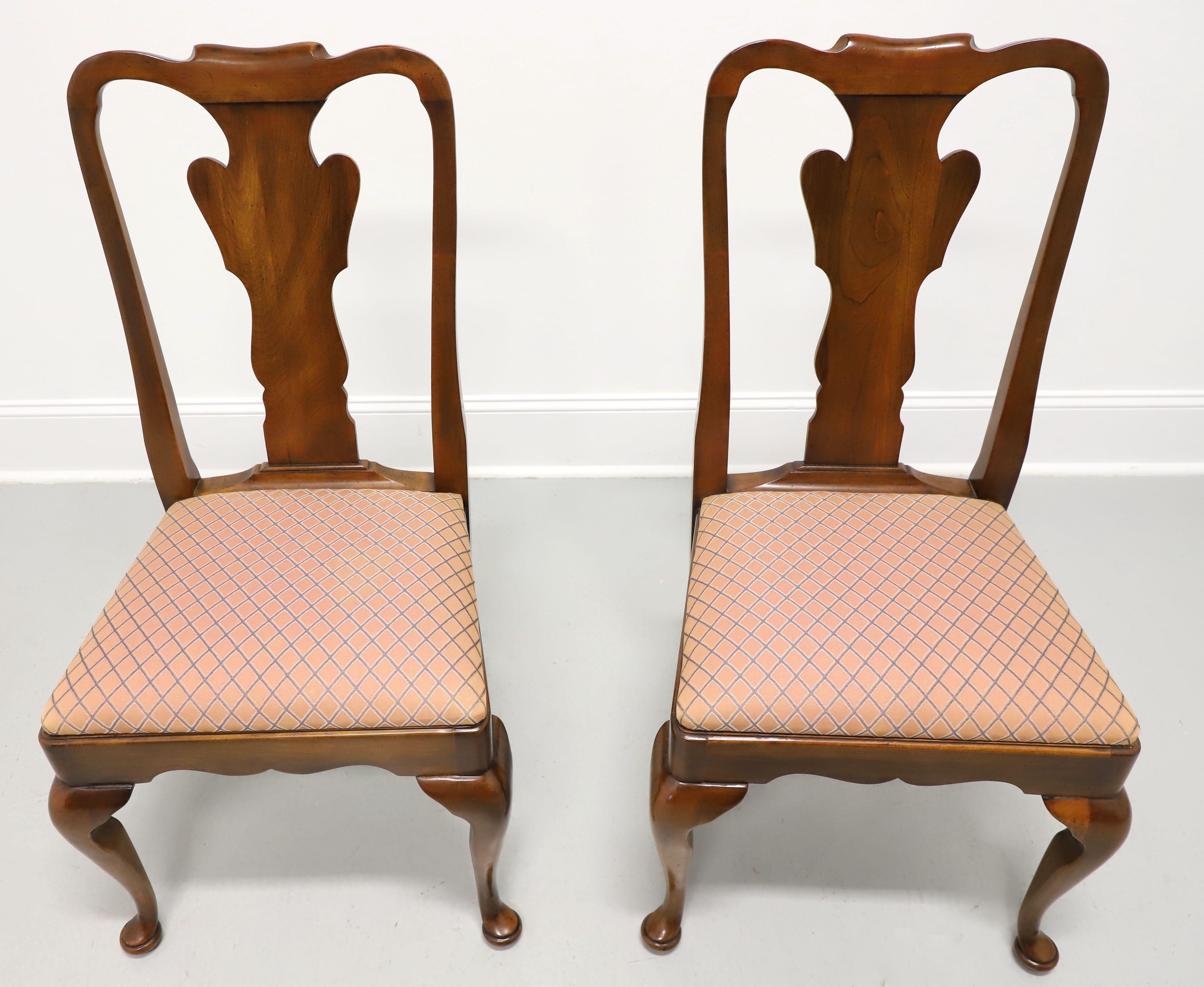 A pair of Queen Anne style dining side chairs by Statton Furniture. Solid cherry wood with their Oxford finish, rounded crest rail, carved backrest & apron, salmon pink color diamond pattern fabric upholstered seat, cabriole legs, and pad feet. Made
