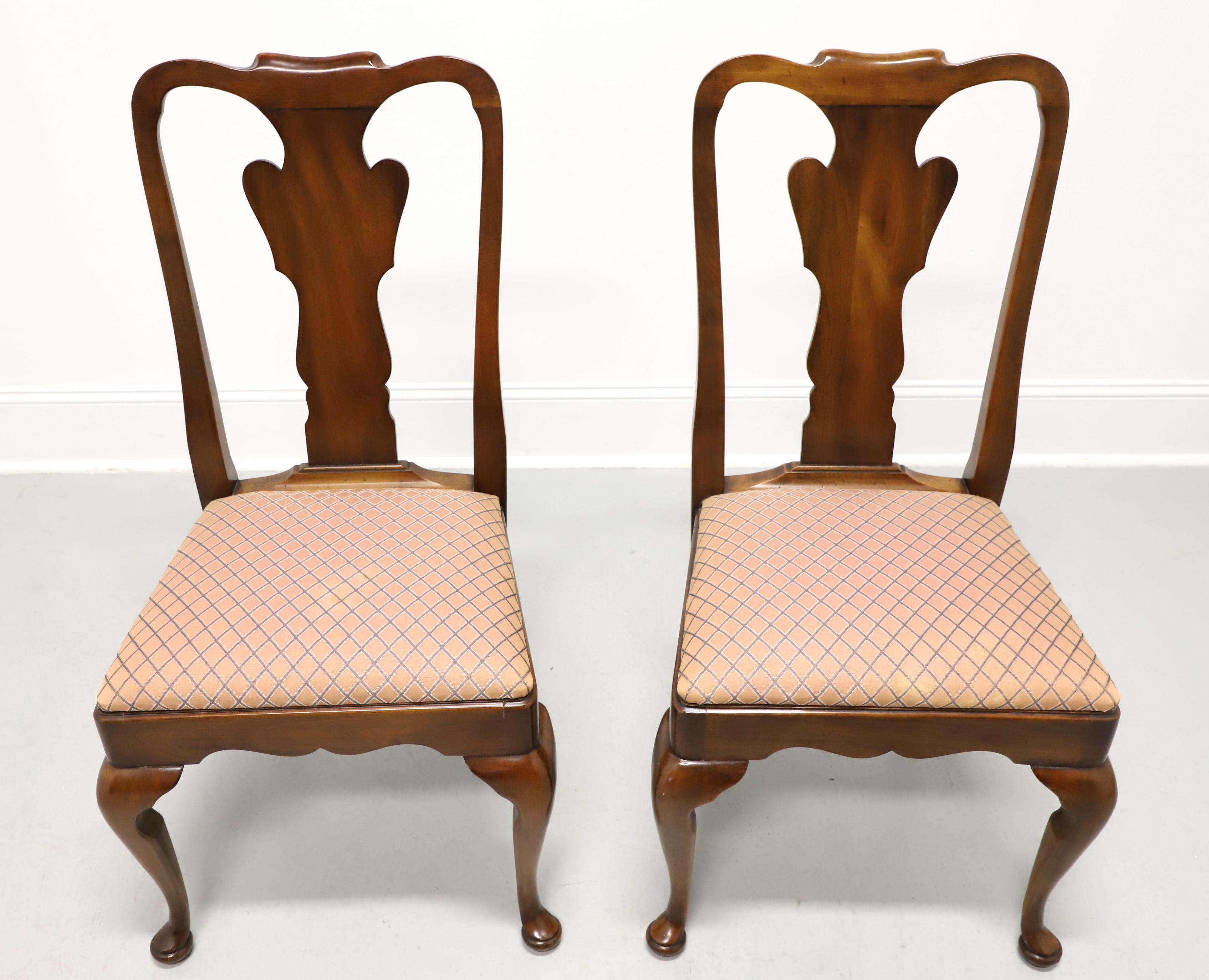 A pair of Queen Anne style dining side chairs by Statton Furniture. Solid cherry wood with their Oxford finish, rounded crest rail, carved backrest & apron, salmon pink color diamond pattern fabric upholstered seat, cabriole legs, and pad feet. Made