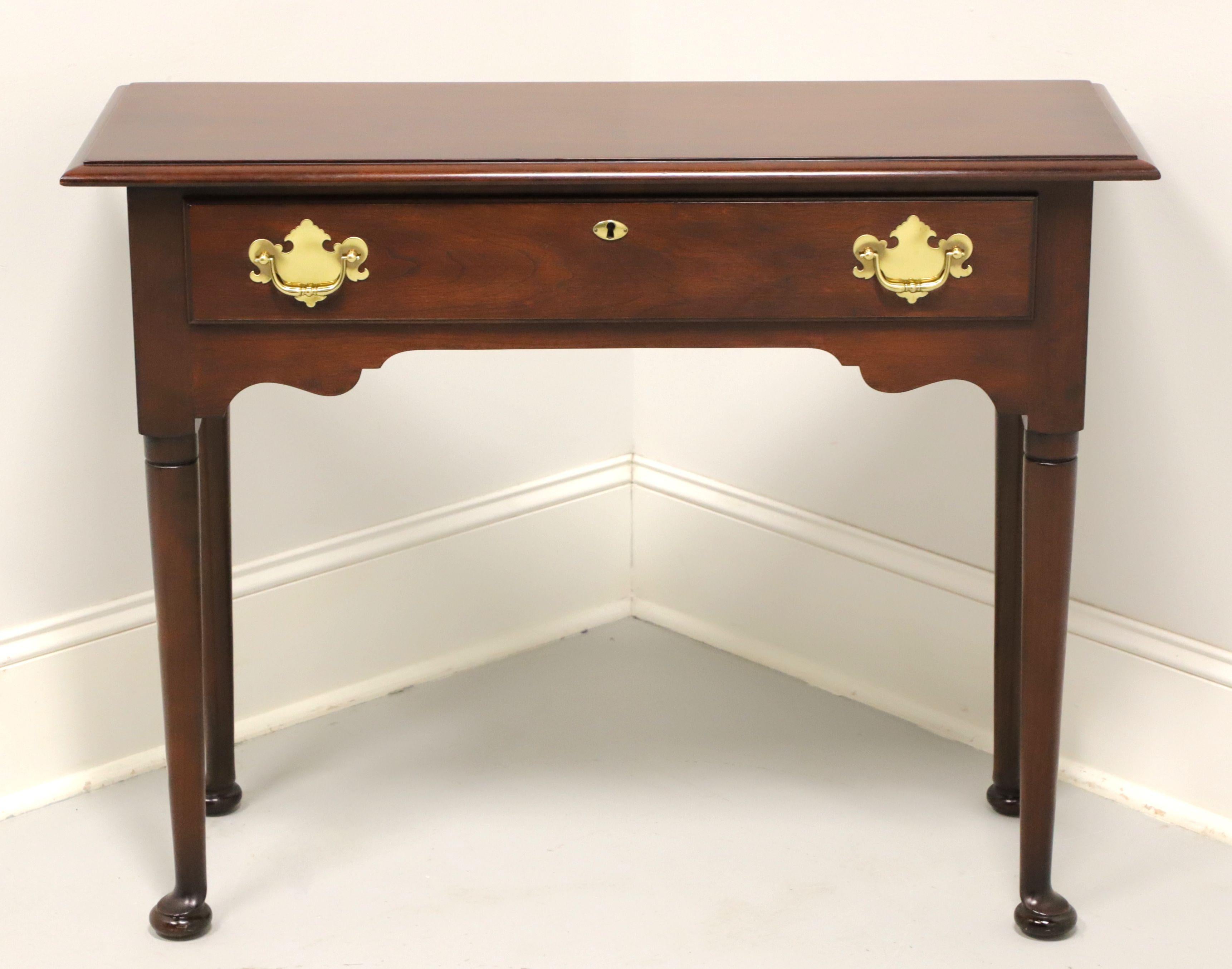 A Georgian style diminutive console table by Statton Furniture, from their Trutype line. Solid cherry wood with their Oldtowne finish, brass hardware, bevel edge top, carved apron, tapered straight legs and pad feet. Features one drawer of dovetail