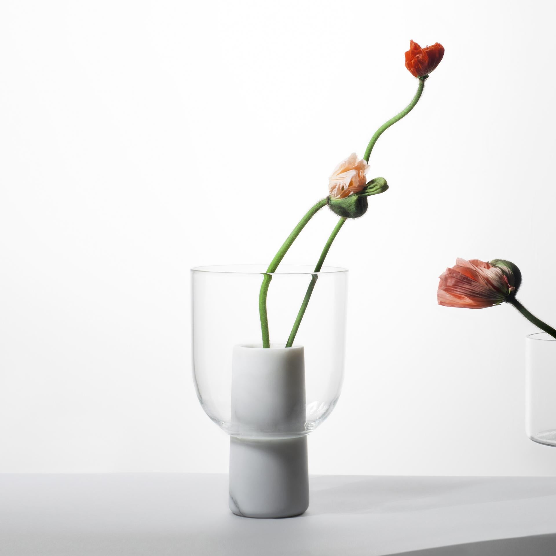 A glass and marble vase to add a touch of softness and detail to the interior. The thin and delicate material of the top contrasts the marble body of the base and creates a layered silhouette. The word 