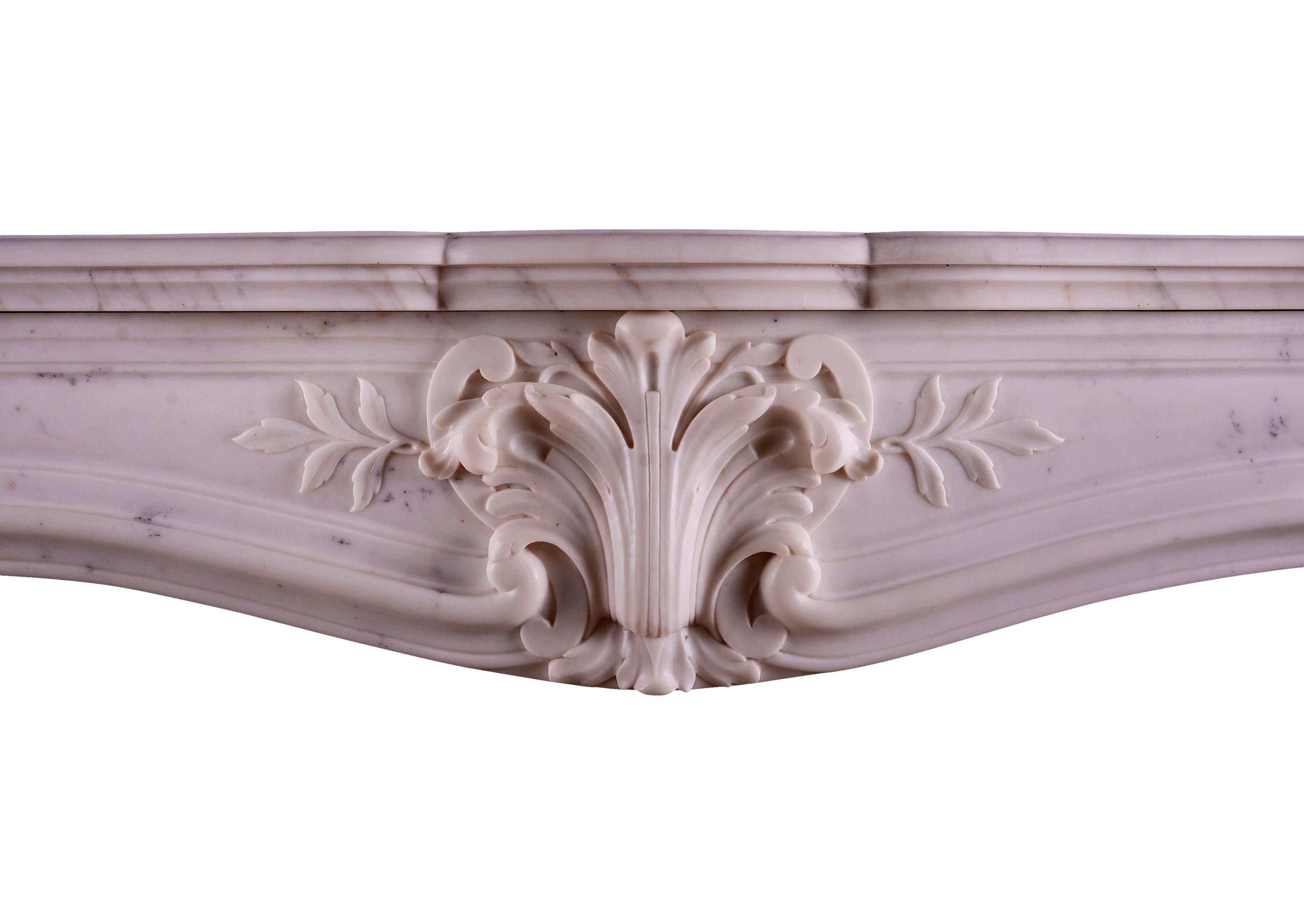 A 19th century statuary marble fireplace in the Louis XV manner. The shaped, fluted jambs surmounted by scrolled shells, the frieze with central cartouche flanked by leaf work. Shaped shelf above, French.

Measurements:
Shelf Width:	        1325 mm