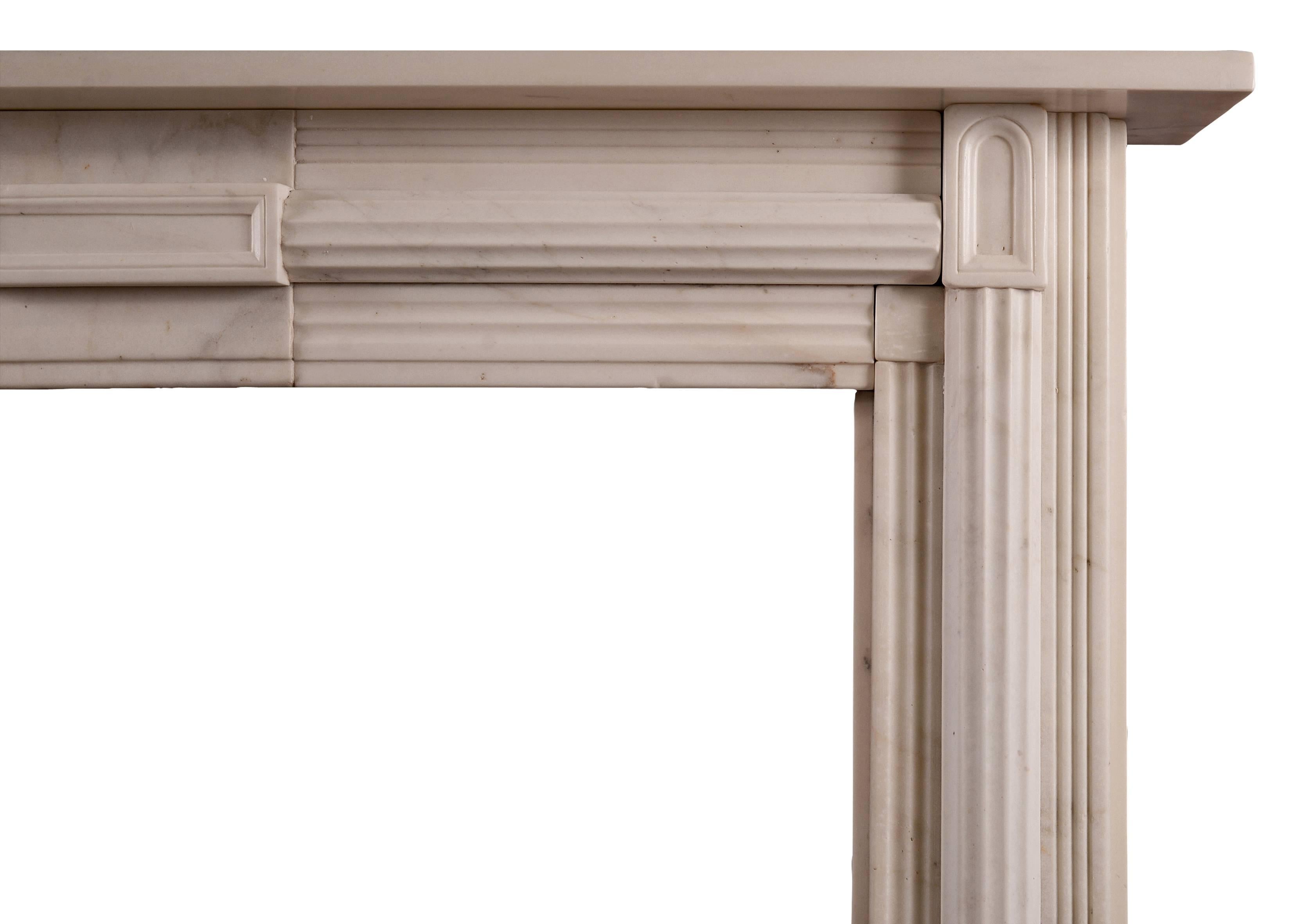 An English statuary white marble fireplace in the Soanian manner. The reeded moulding to jambs and frieze with centre plaque and arched end blockings, 19th century.

Measurements:
Shelf width: 1345 mm / 53 in
Overall height: 1145 mm / 45 1/8