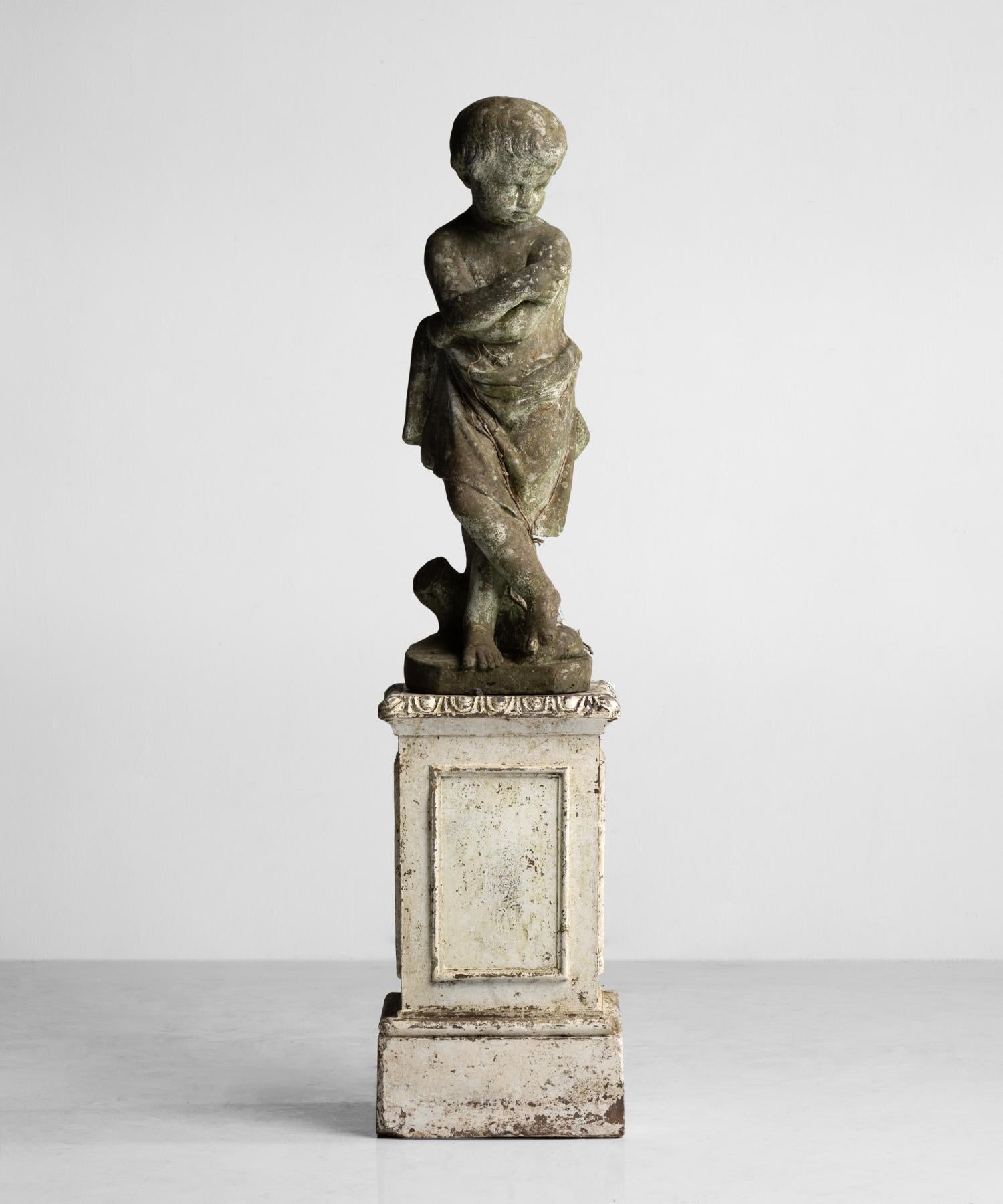 Beautifully patinated figure in dark stone atop a pedestal in original paint.