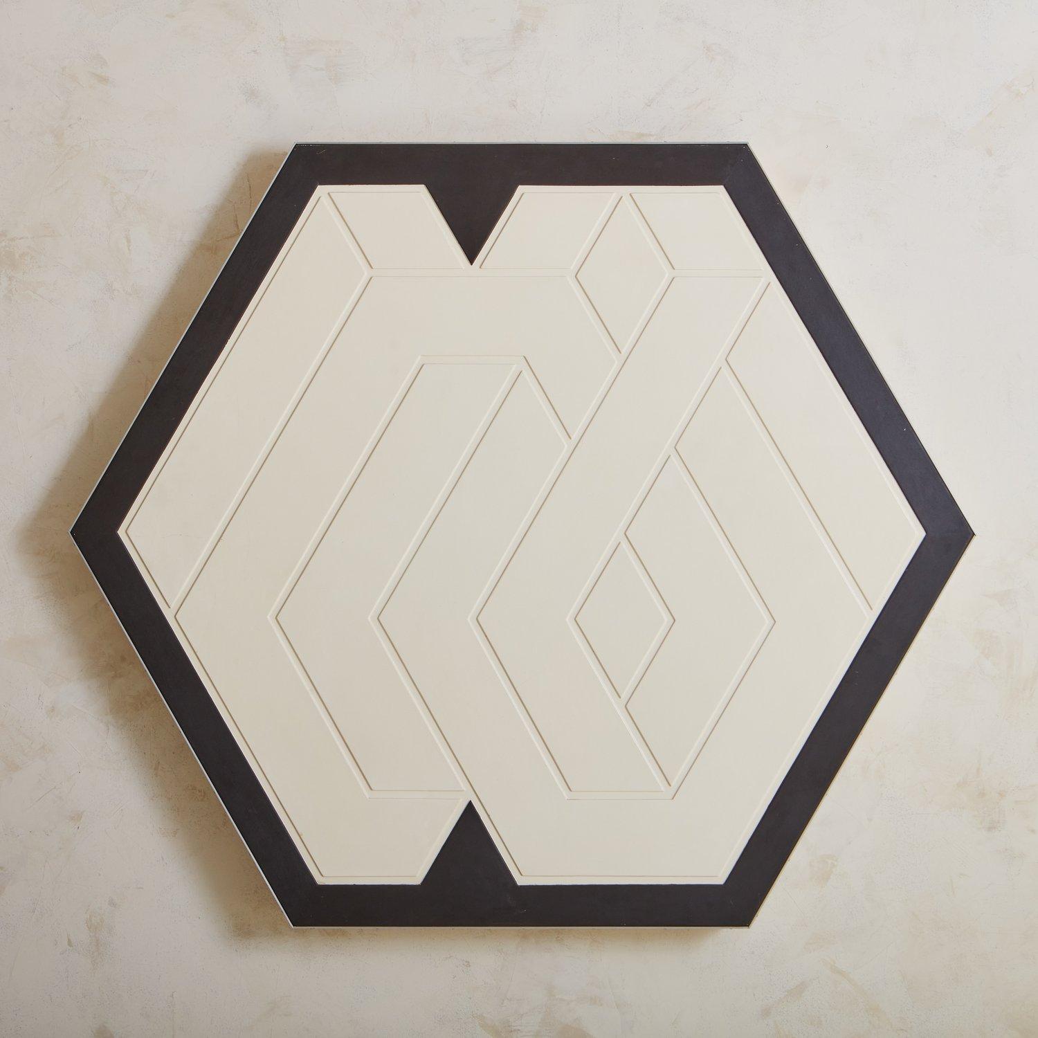 A large-scale wall sculpture titled ‘Statum’ by E.T. Frankland. This striking hexagonal piece has a black painted wood background with a cream lacquered wood textured geometric pattern. With a 3” depth, this piece commands attention and floats