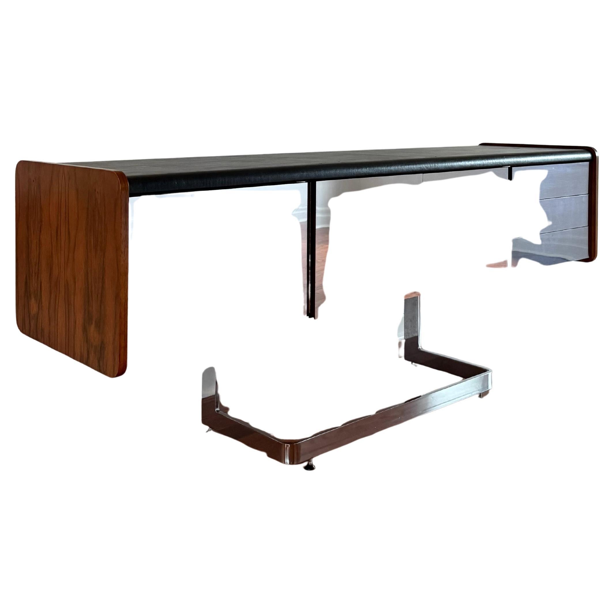 Fabriqué en bois de rose avec des portes et des tiroirs en miroir. Base chromée en porte-à-faux avec pieds autonivelants et surface enveloppée de cuir ; le tout en bon état vintage [voir les photos pour les défauts mineurs]. Équipé d'un tiroir à