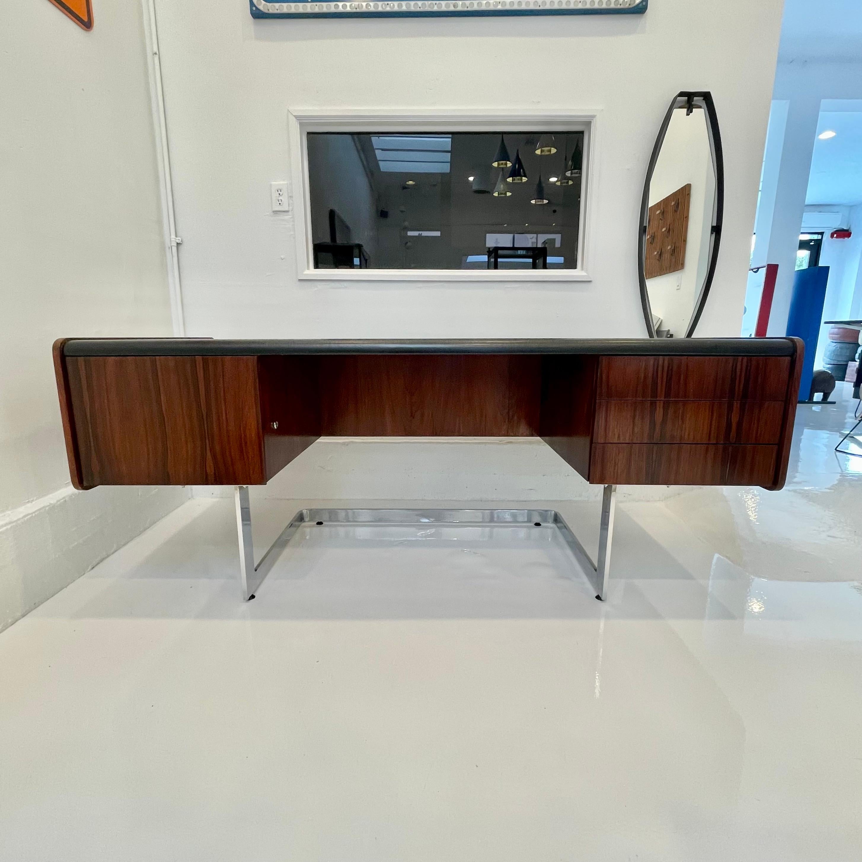 Stunning rosewood desk by Ste. Marie & Laurent. Desk floats on top of newly polished chrome base. Entire desktop is wrapped in a black vinyl. Three pull-out drawers on right side of desk with one large file drawer on the left. Original lock and keys