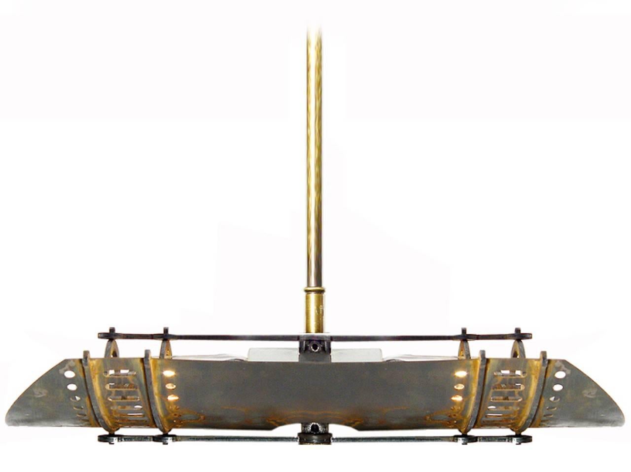Cet abat-jour en acier ventilé a un aspect industriel mais reste futuriste. Le pendentif mesure 20,3 cm de long et 12,7 cm de large. L'abat-jour aux courbes douces comporte deux rangées de découpes qui projettent des motifs subtils et protègent les