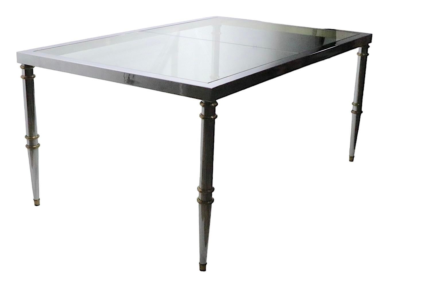 Exceptional chrome, brass and glass extension dining table in the manner of Maison Jansen, probably made in Italy, circa 1970s - unsigned. The table has tapering pole legs, with brass rings and bras feet. The chrome top has a brass interior which