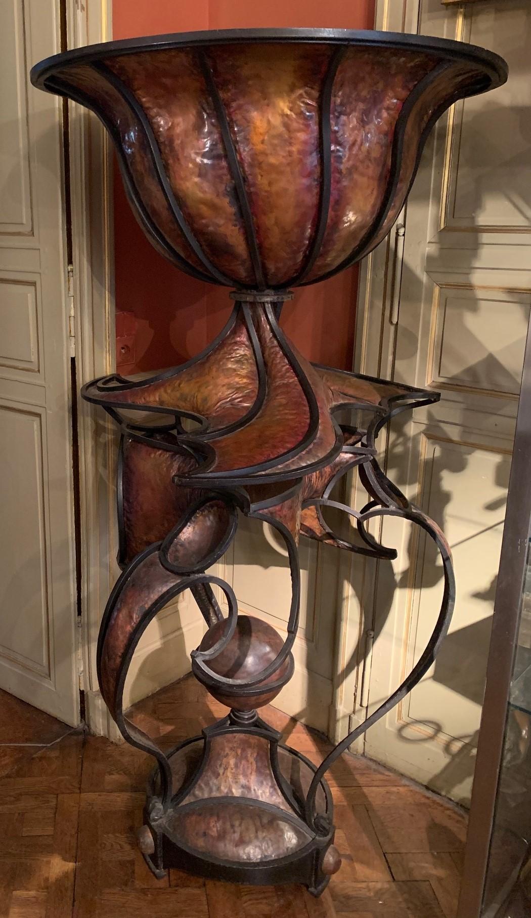 Pflanzgefäß aus Kupfer und Schmiedeeisen, oben eine große, ausgestellte Schale, alles auf einem runden Dreibein-Sockel ruhend.
André Dubreuil wurde 1951 in Lyon geboren und starb im April 2022.
Er war einer der einzigartigsten Schöpfer seiner Zeit.