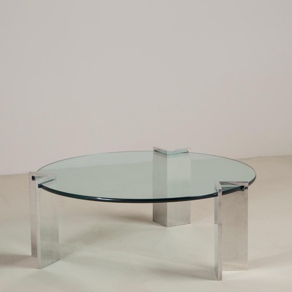 A circular glass top coffee table sat inside three steel legs designed by Leon Rosen for Pace, 1970s.

The Pace Collection was founded by Leon and Irving Rosen in 1960. Their furniture style included exotic wood veneers and high lacquer finishes