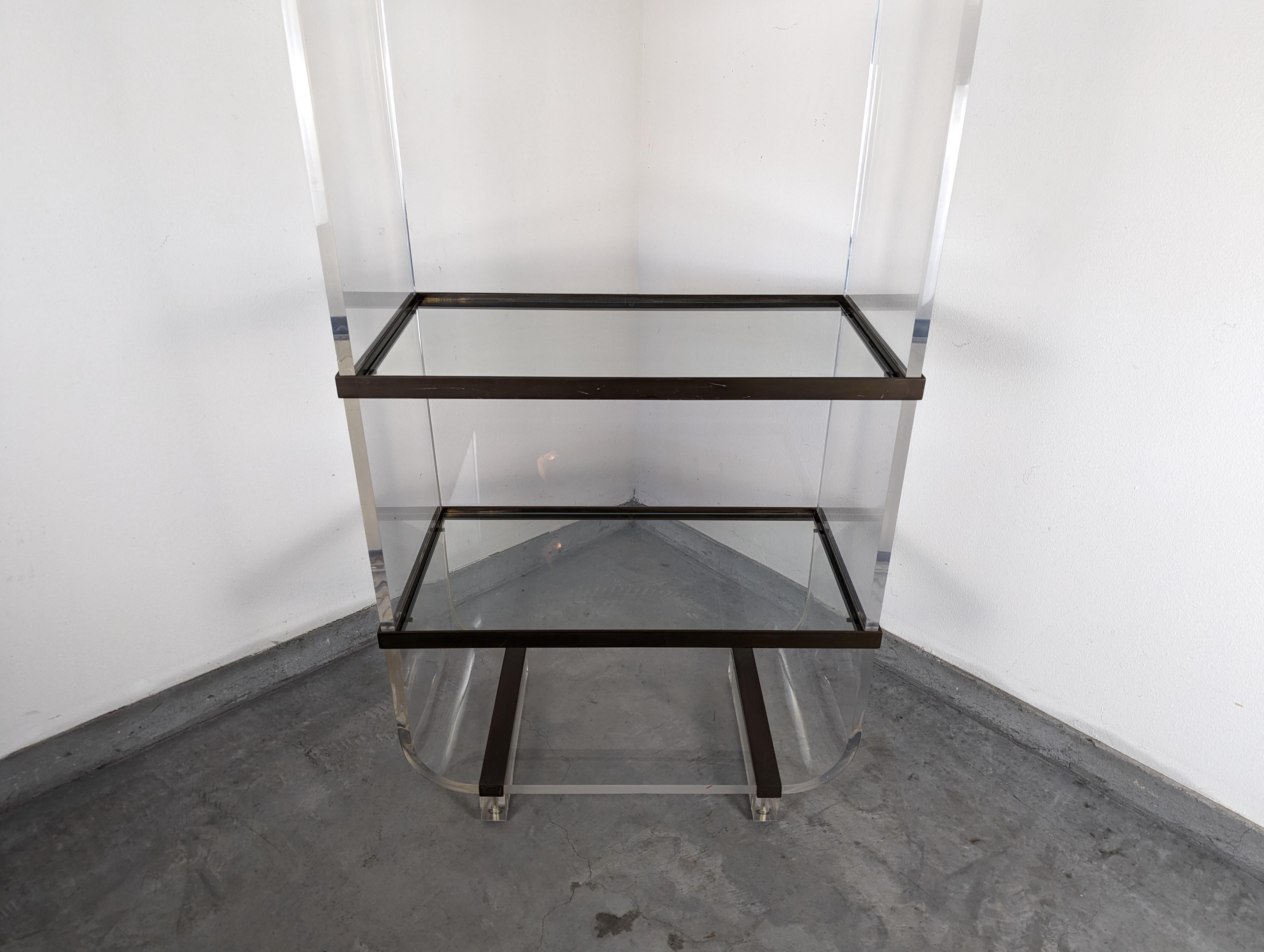 Entra nell'epitome del glamour vintage con questa straordinaria etagere postmoderna in lucite, attribuita all'iconico designer americano Charles Hollis Jones, noto per il suo lavoro pionieristico con l'acrilico e la lucite negli anni Settanta.