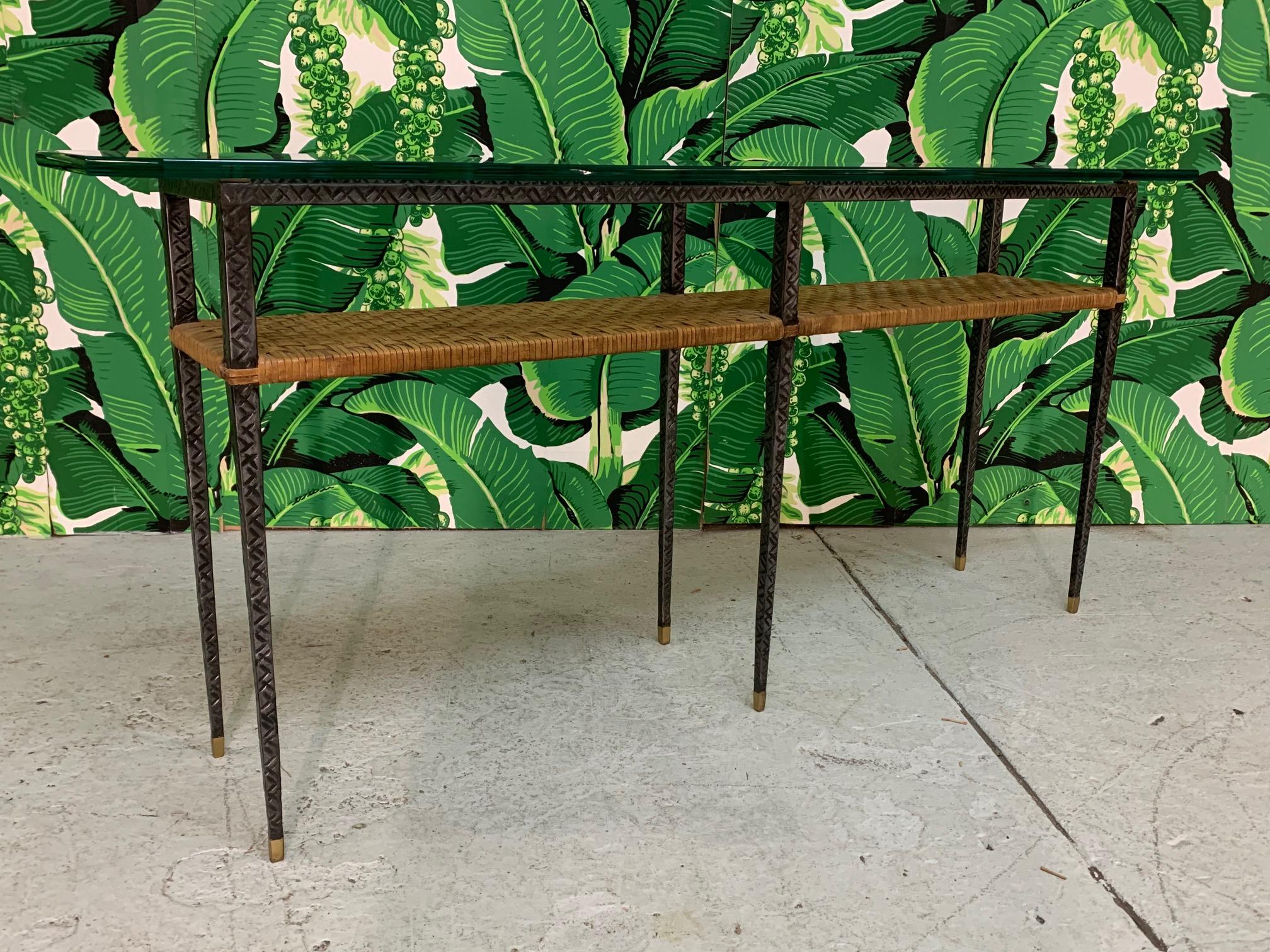 Mixed-media console table features a metal frame with diamond cut detailing, brass accents, rattan center shelf, and a glass top. Very good condition with only very minor imperfections consistent with age. Glass top measures 60