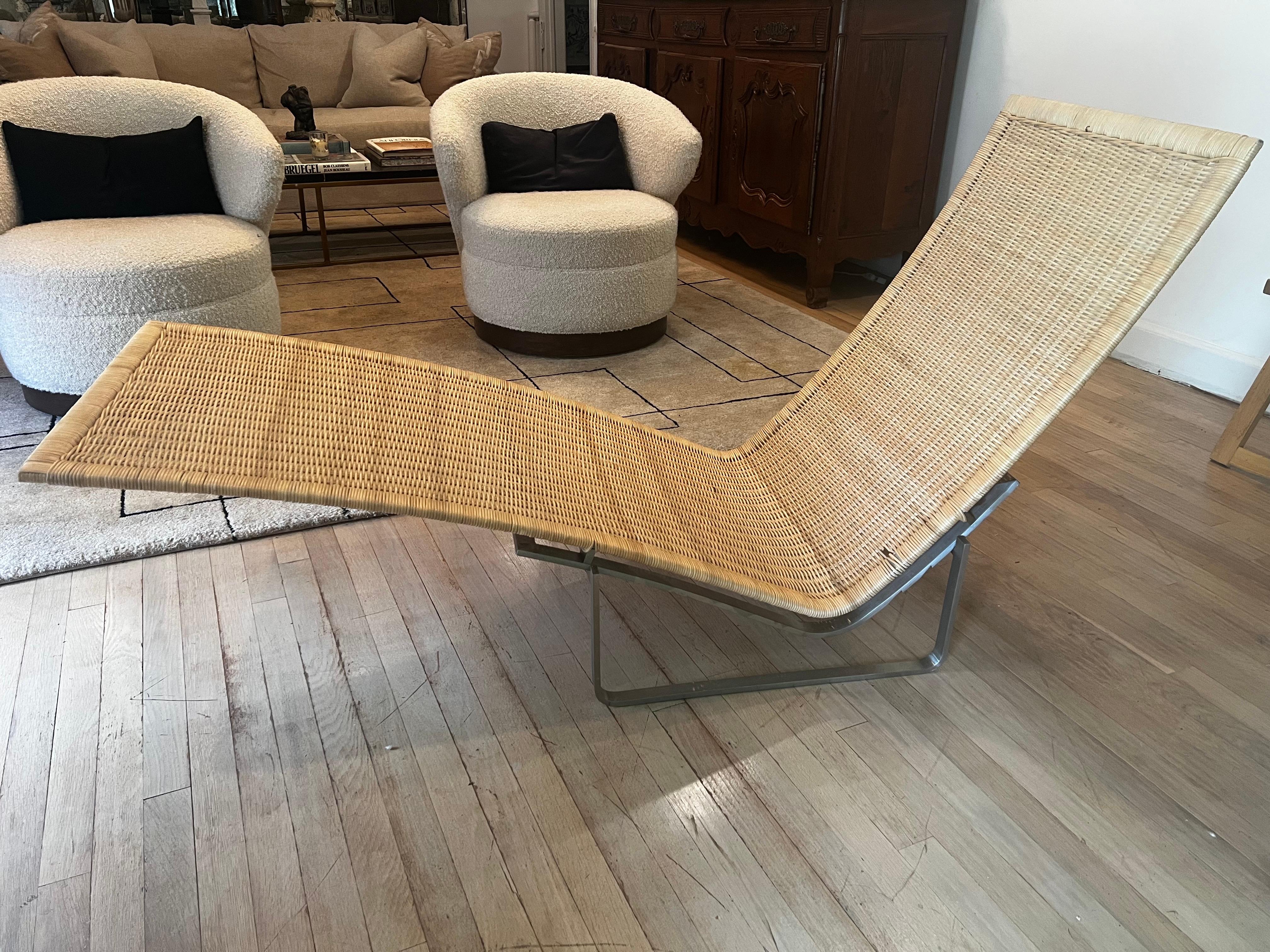 Esta tumbona combina la elegancia natural con un diseño funcional.  El asiento y el reposapiernas están formados por mimbre de tejido tupido, que confiere a la silla un aspecto ligero y orgánico, mientras que la elegante estructura metálica