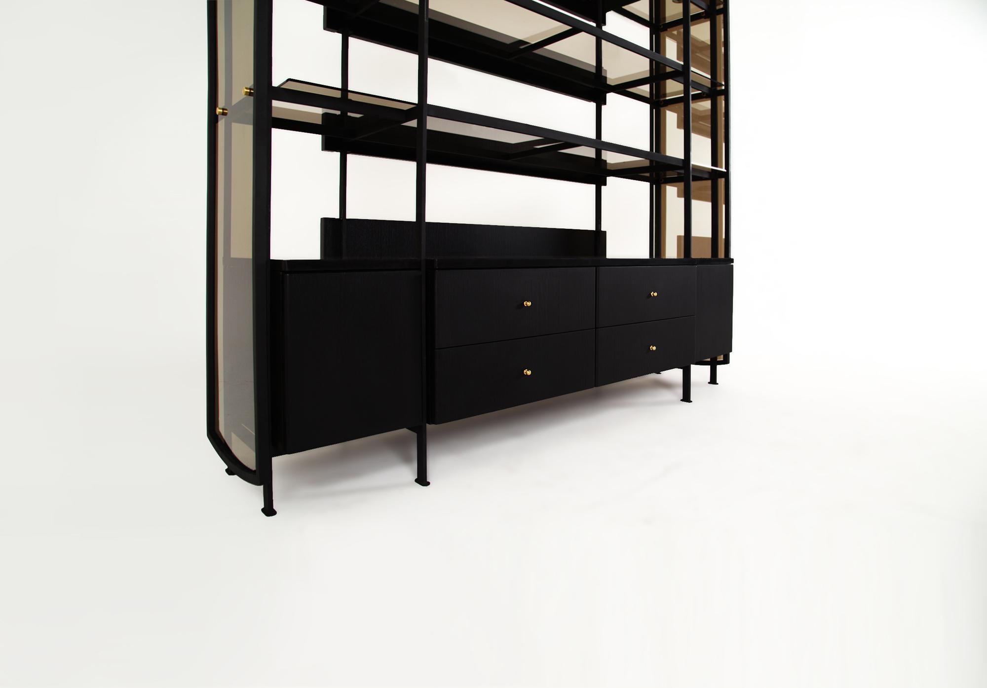 The Collector's cabinet is constructed in blackened steel combined with a blackened oak cabinet fitted to its interior. The cabinet is weighed down with black marble and is intersected by the cabinets’ frame. One-way reflective bronze glass hugs the