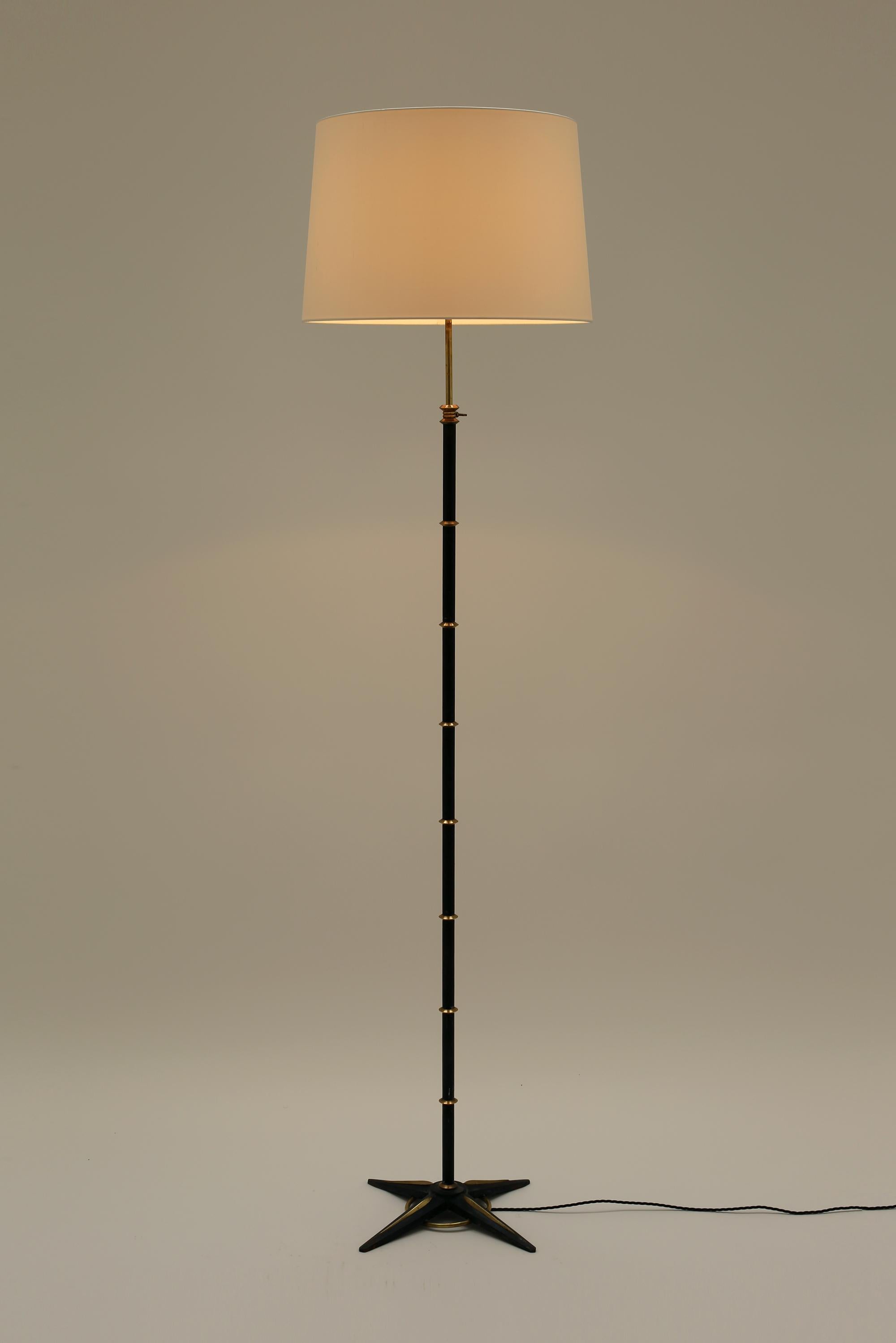 A blackened steel, brass and cast iron adjustable floor lamp by Gilles Sermadiras for Galerie Maison et Jardin. French, c. 1950. Often attributed to Jacques Adnet. Supplied with an off-white dupion silk Empire shade.