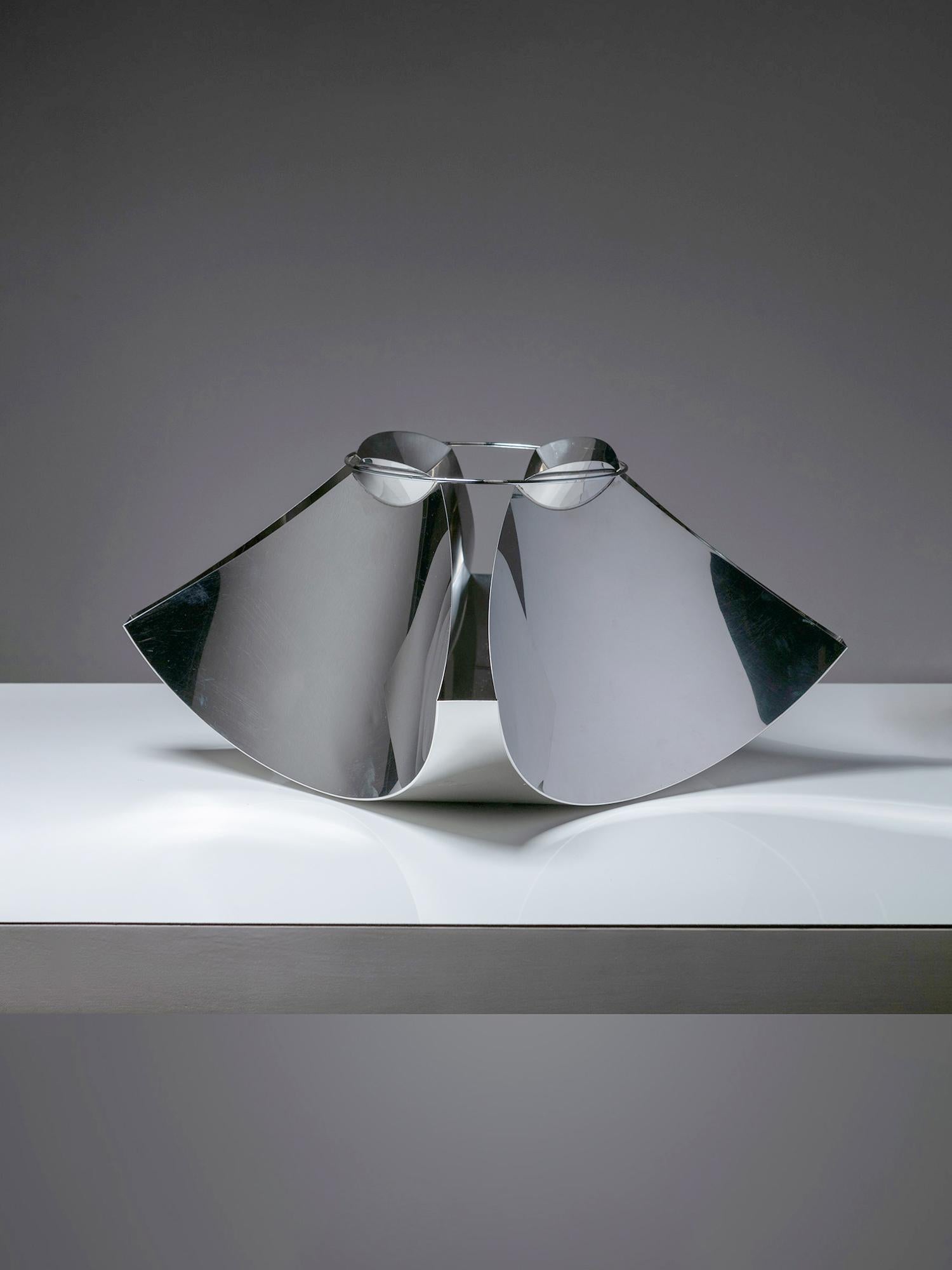 Mittelstück aus Edelstahl von Gian Casè für Robots.
Im Origami-Stil gefaltetes Metallblech, das durch einen oberen Metallring in Spannung gehalten wird.