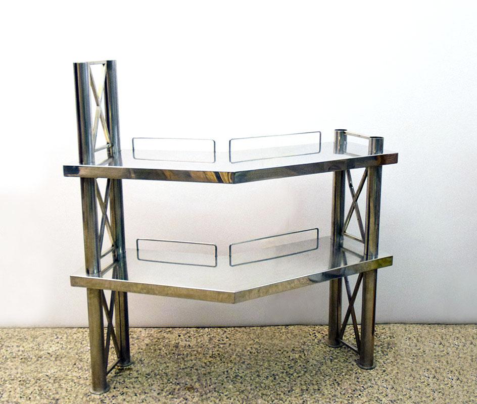 Console in polished steel, Italian production from the 70s.
Composed of two trellis columns and two corner shelves, ideal as a hi-fi system holder, bar counter or object holder, with the possibility of also being fixed to the wall on one side.
In