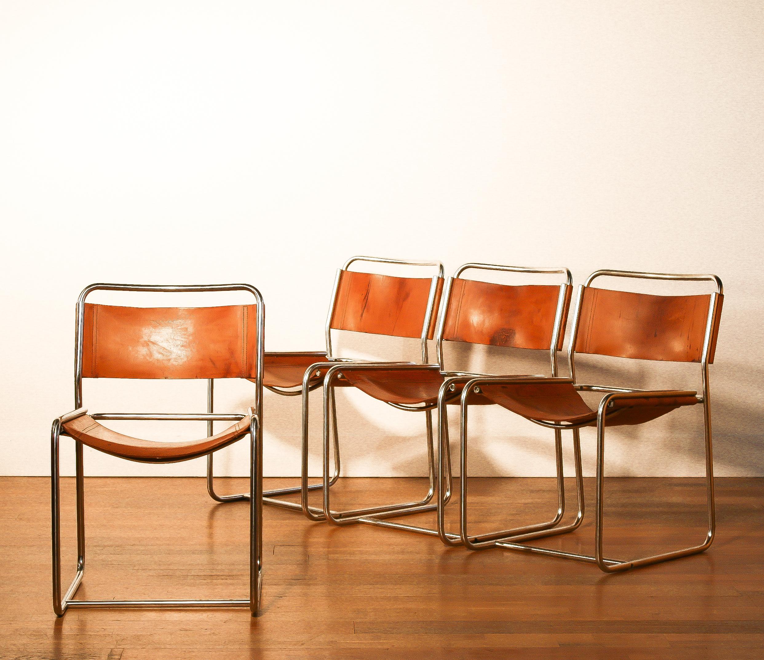 A nice set of four dining chairs designed by Paul Ibens & Clair Bataille.
The seat and the backrest are made of sturdy cognac leather. 
The frame consists of a steel tube that is shaped like a cube. 
The chairs are in a very nice used