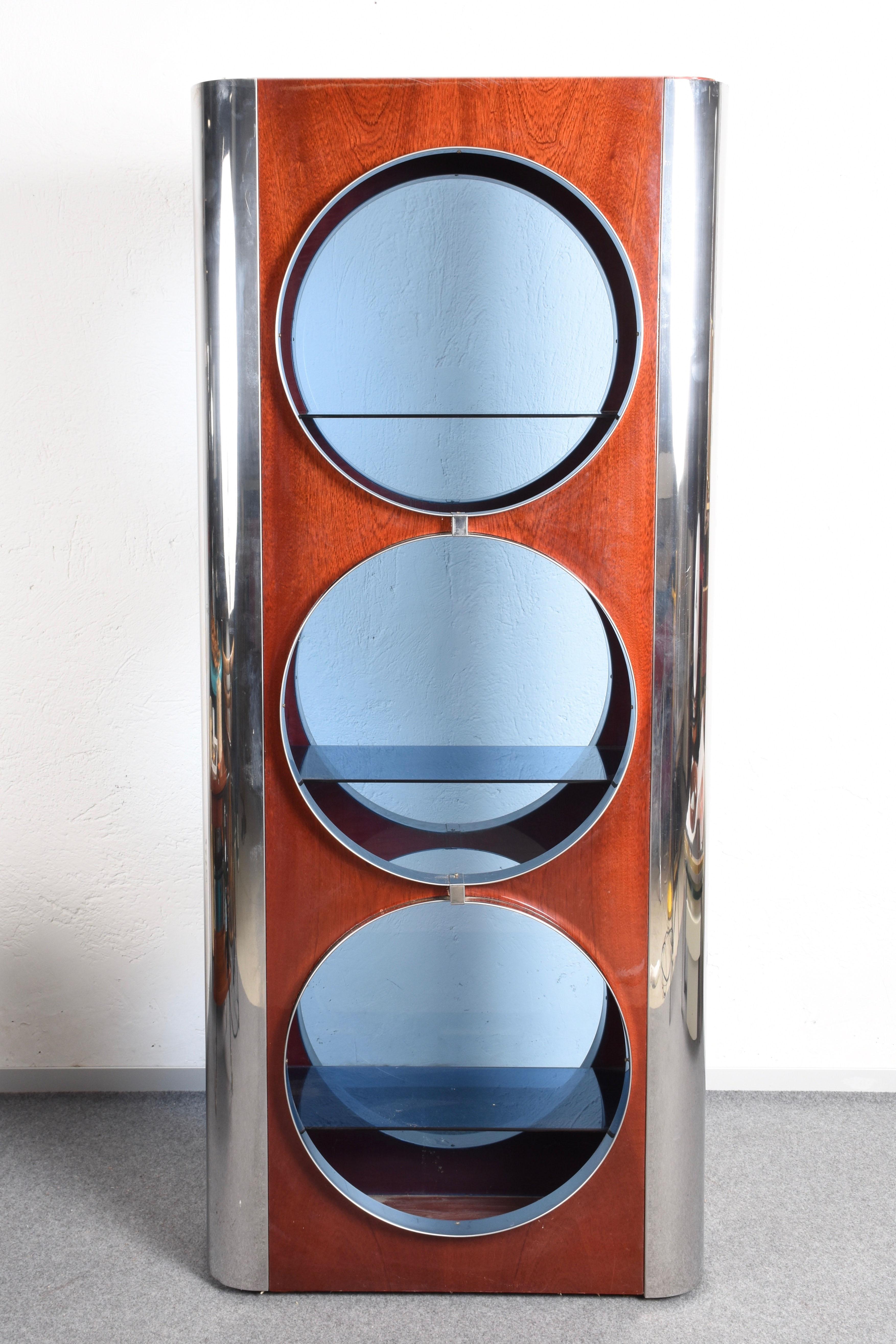 Magnificent Italian showcase-bookcase from the 1980s attributed to Willy Rizzo. 

It is made of stainless steel, mahogany and the internal surfaces and the round glass windows on the back of the portholes are smoky blue glass.

In late 1948,