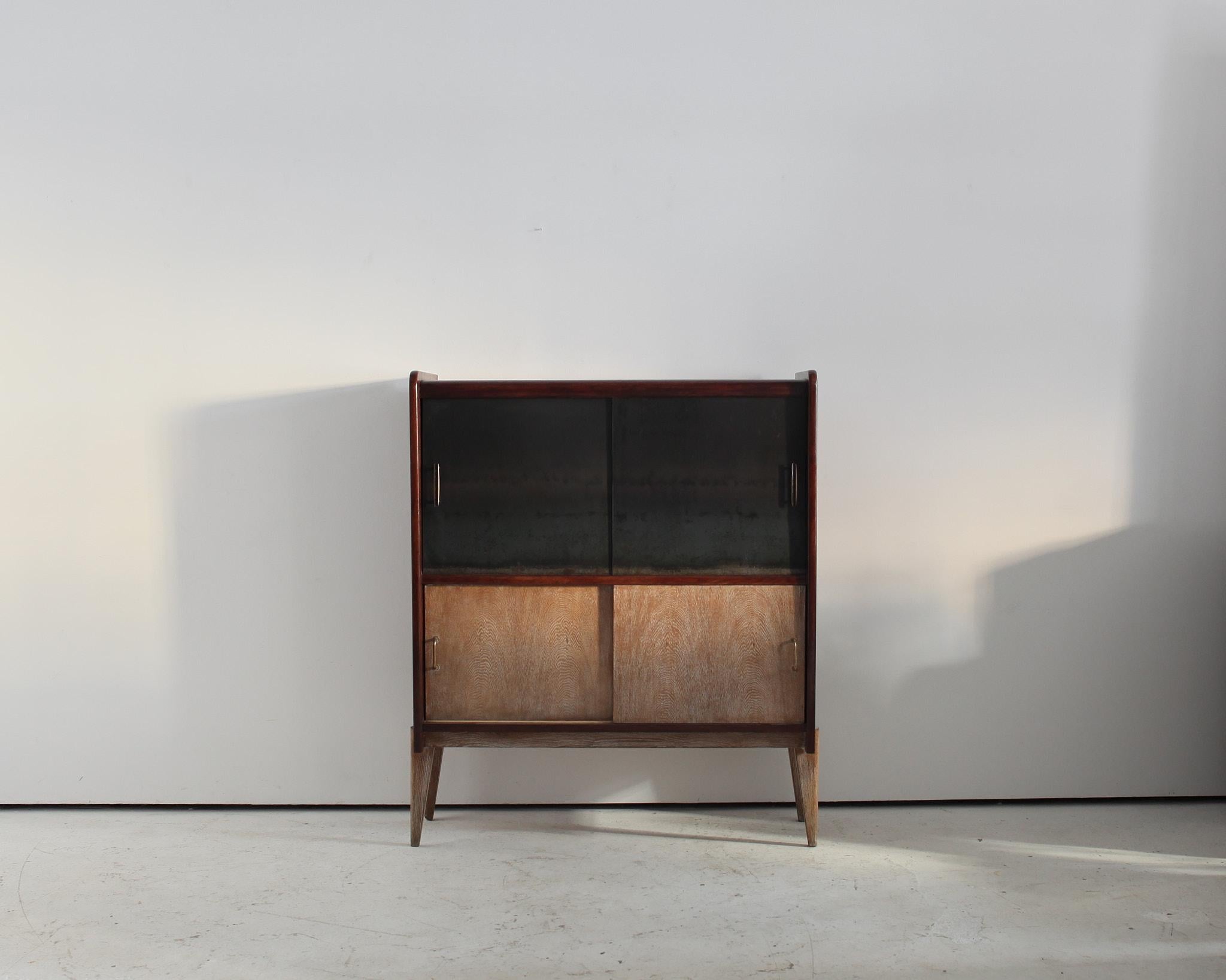 A unique 1950s French modernist cabinet.

Constructed in oak with two pairs of sliding doors with brass hardware, one steel, one limed oak.

Stylistically with nods to both the deco and modernist design movements.