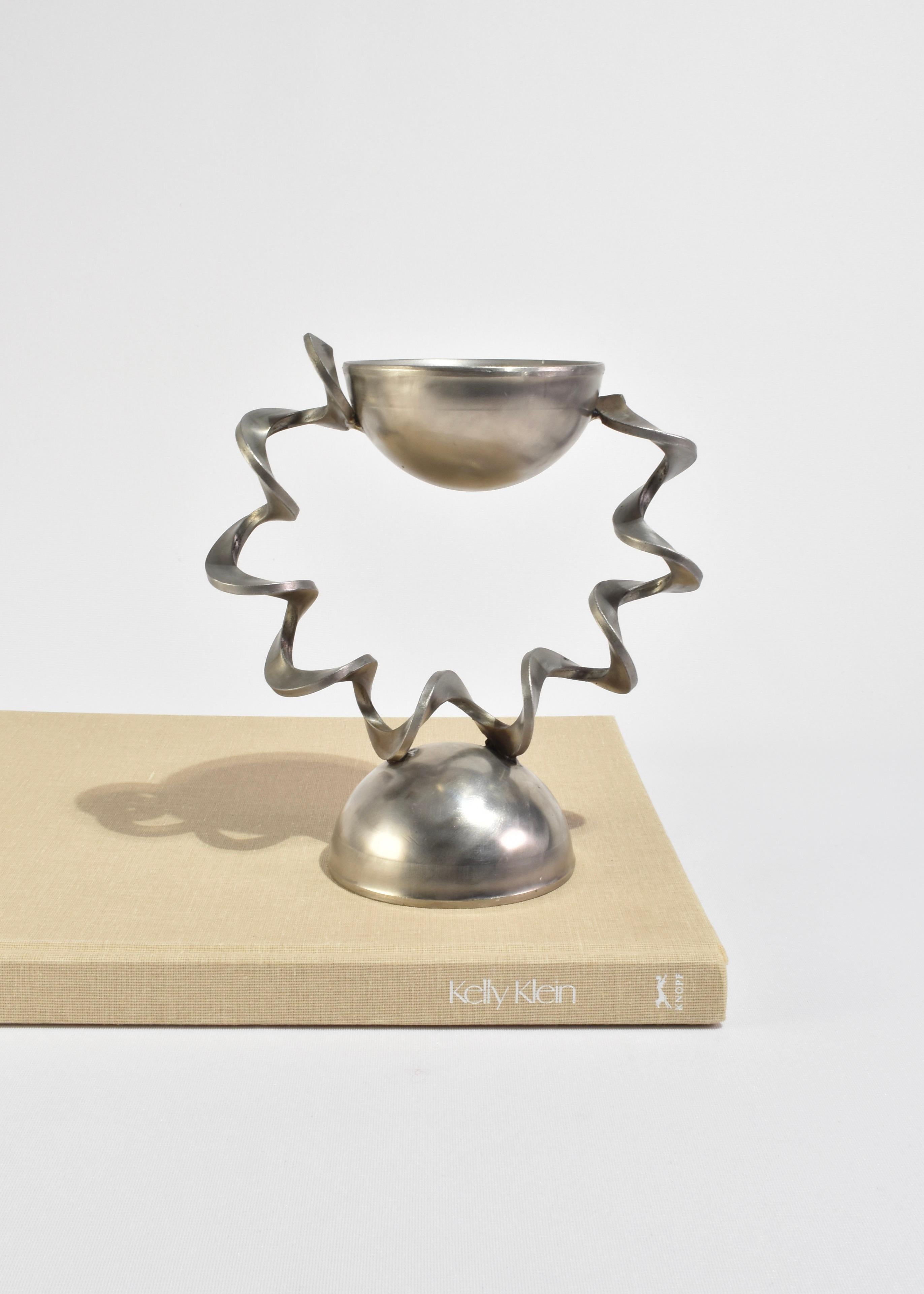 Rara scultura in acciaio saldato con due forme di ciotola e dettagli in bobina, firmata Ann Sperry. 

Lo stile distintivo di Ann Sperry (1934-2009) fonde materiali industriali con forme organiche e astratte, creando sculture che trasmettono un senso
