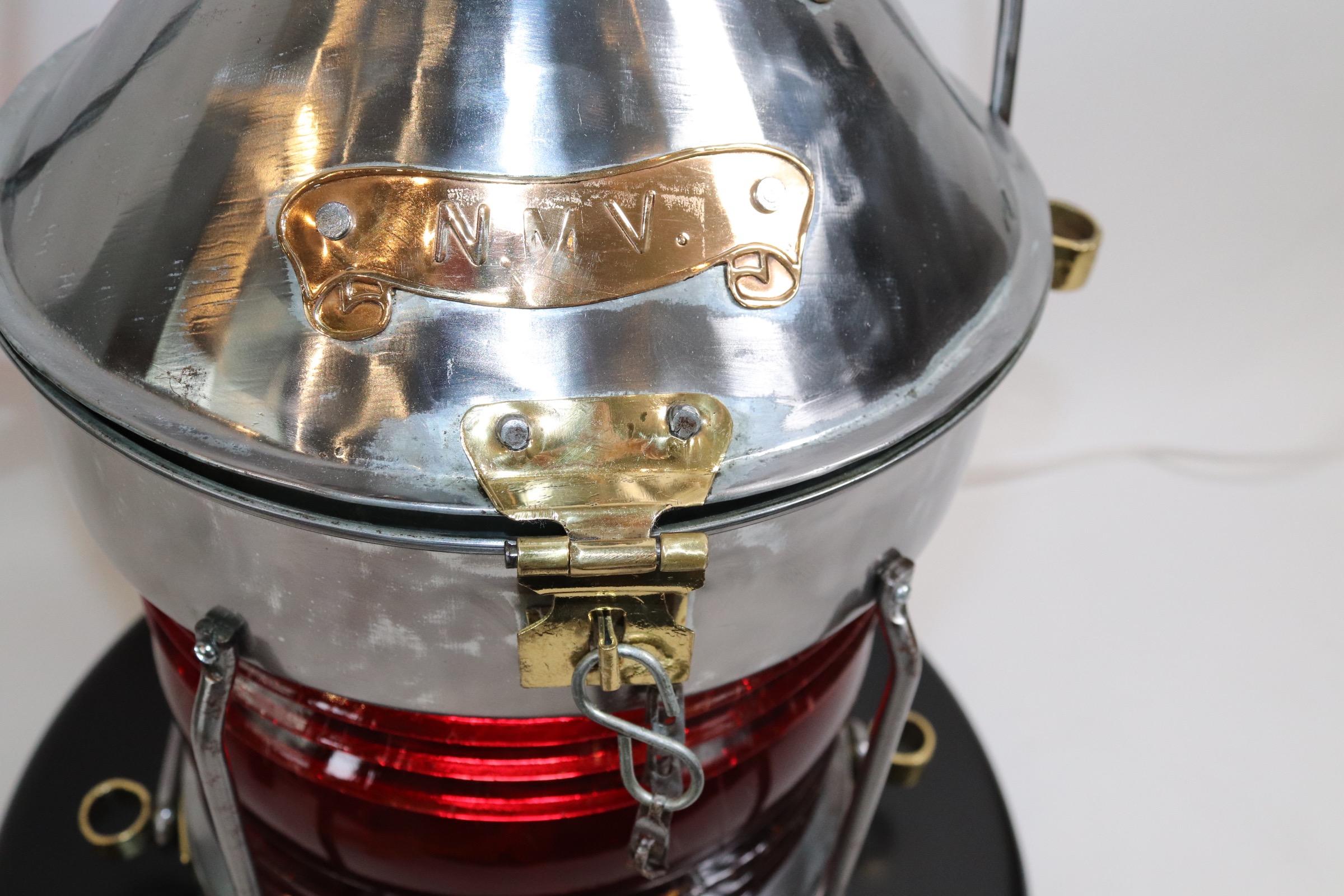 Polished steel ships not under command lantern with rich ruby red fresnel lens. Lantern is mounted to a thick wood base with routed edge and dark finish. Lantern has been electrified for home display. Weight is 24 pounds.